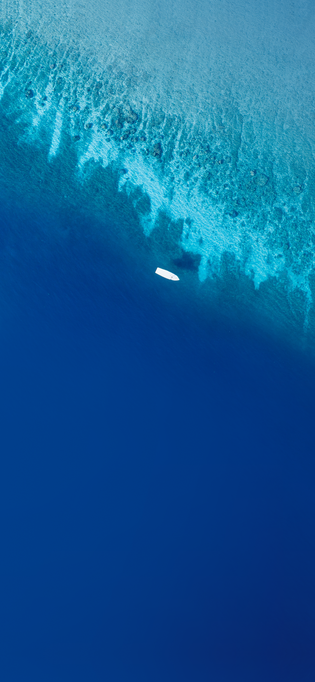 Aerial view of a white boat on blue ocean water near coral reef HD Phone Wallpaper
