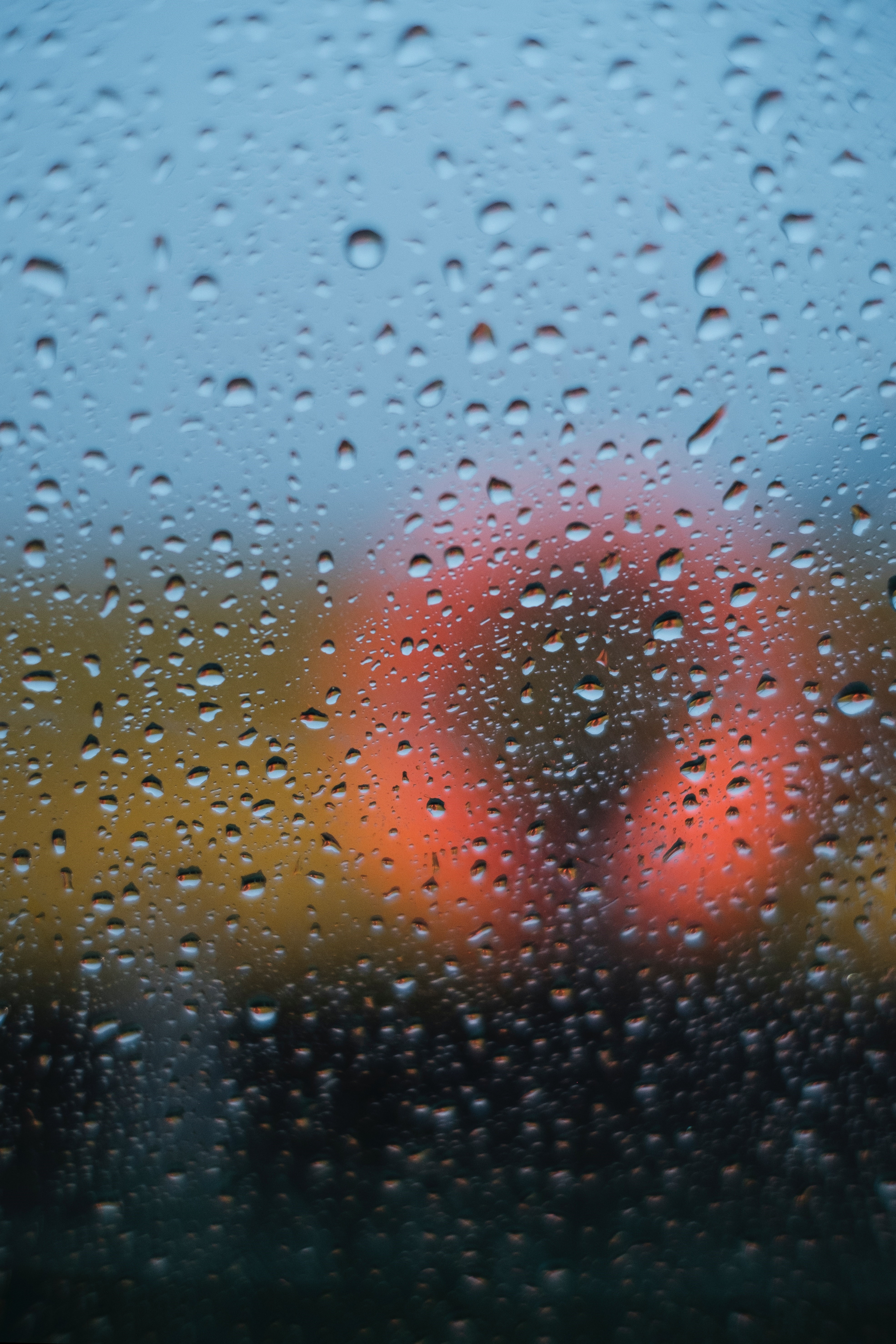 Raindrops on a window with blurred orange and yellow background HD Phone Wallpaper