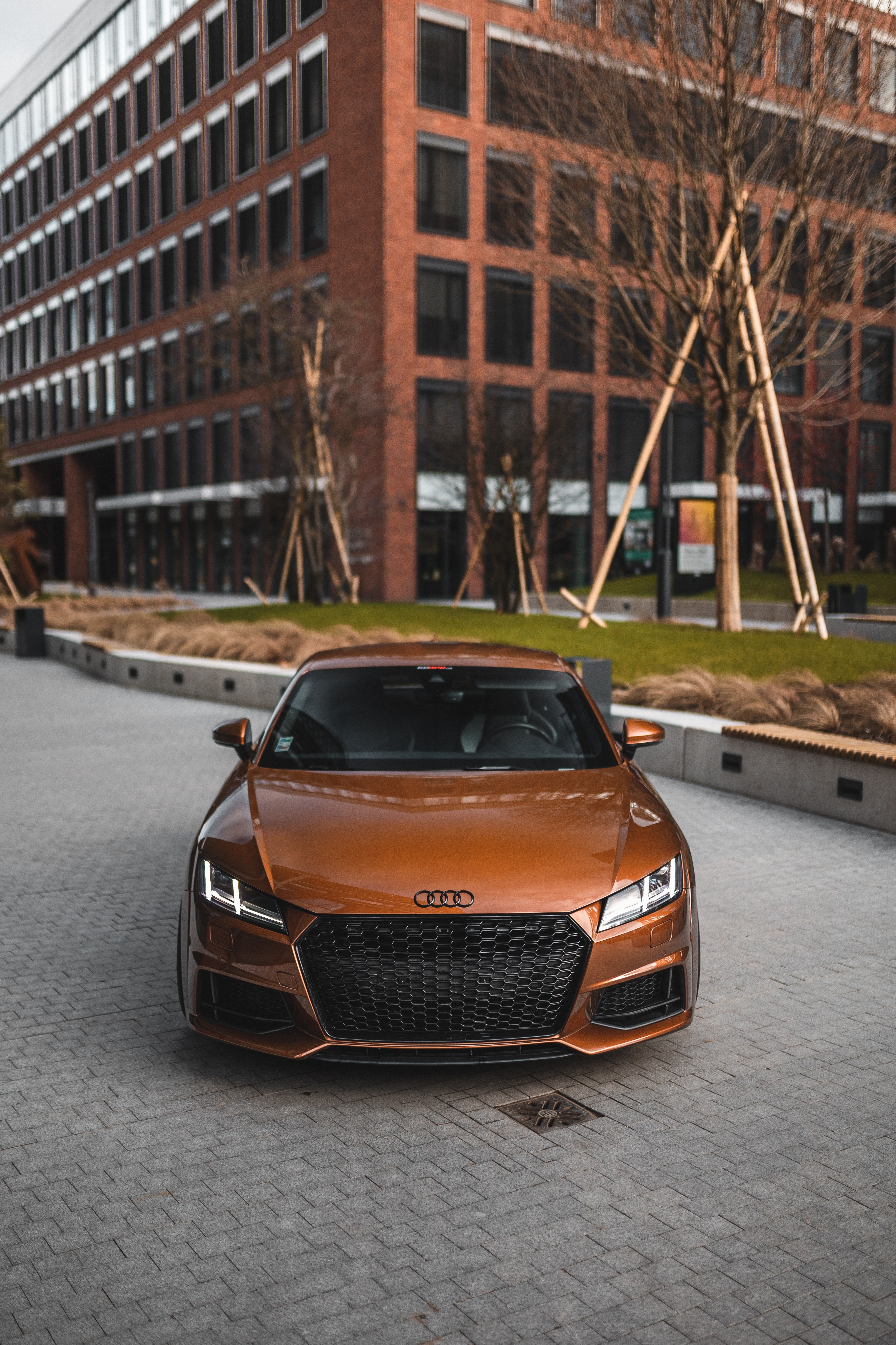 Orange Audi TT sports car parked in front of a modern building HD Phone Wallpaper