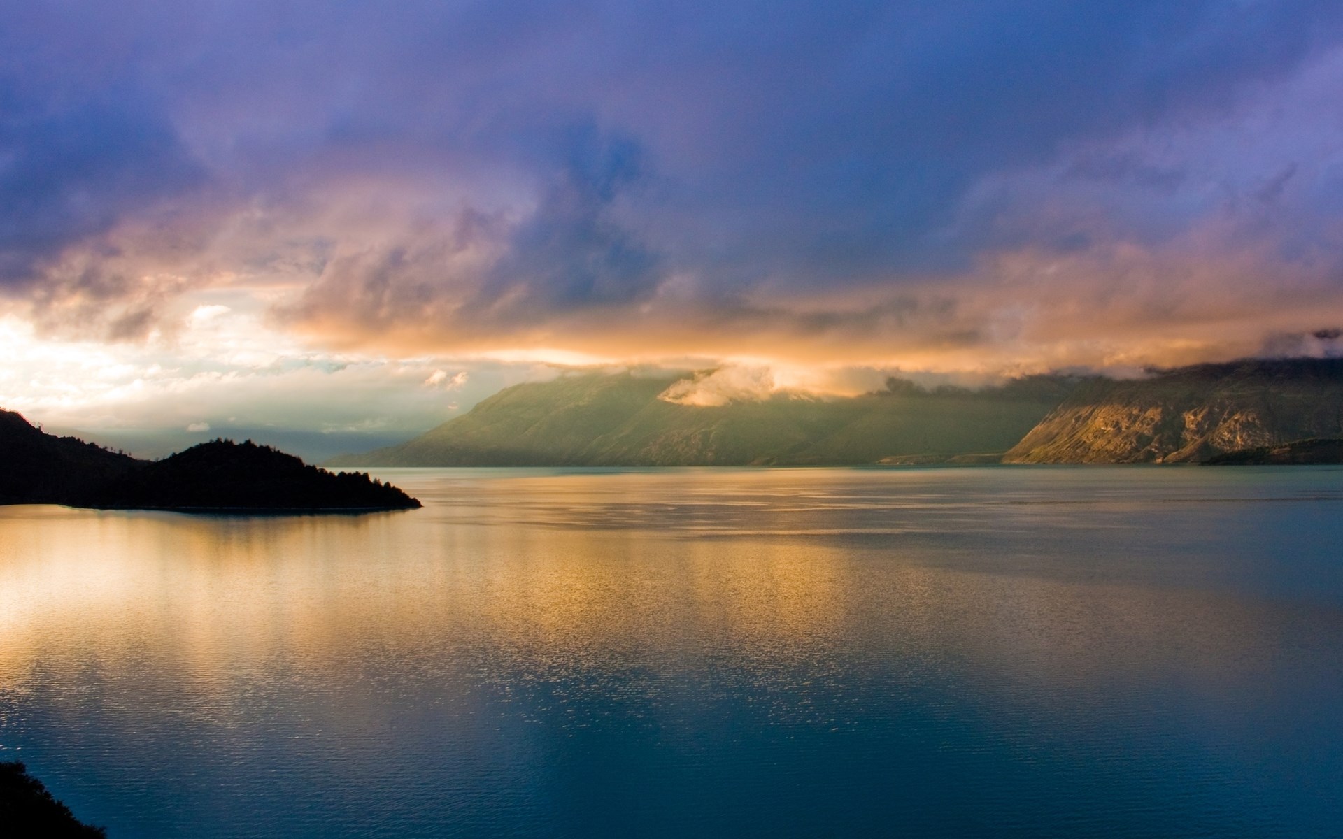 Sunset over a calm lake with mountains and clouds HD Wallpaper