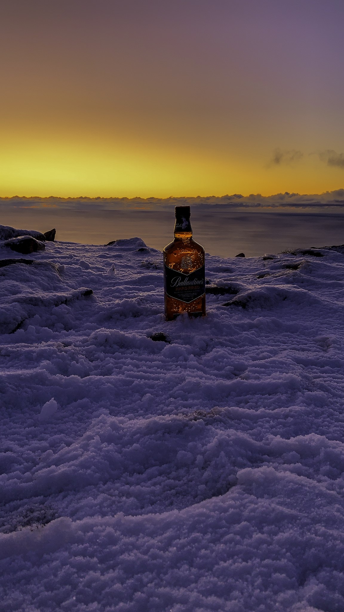 Ballantine's whisky bottle in snow at sunset HD Phone Wallpaper