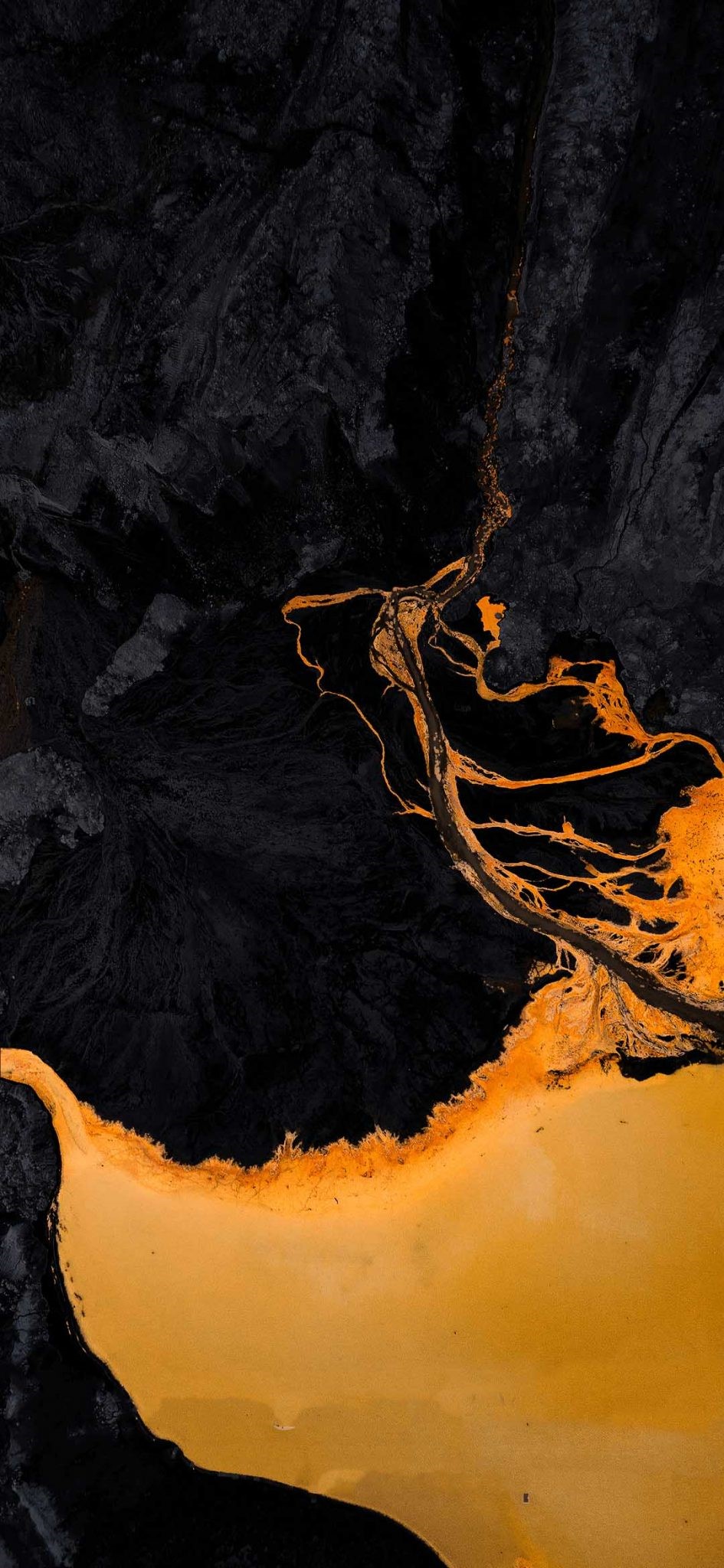 Aerial view of dark volcanic rock and orange river delta HD Phone Wallpaper