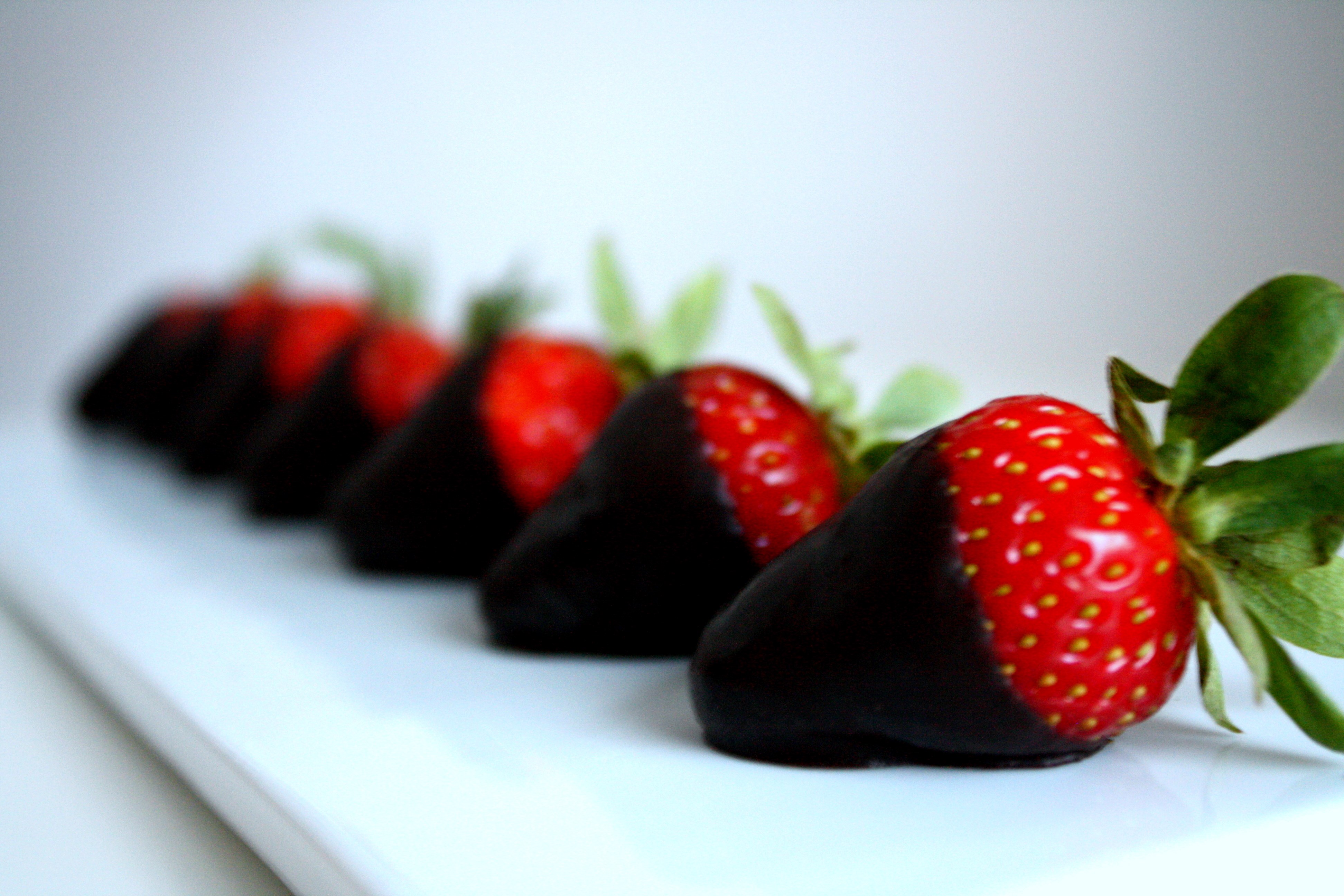 Chocolate-dipped strawberries on a white platter HD Wallpaper