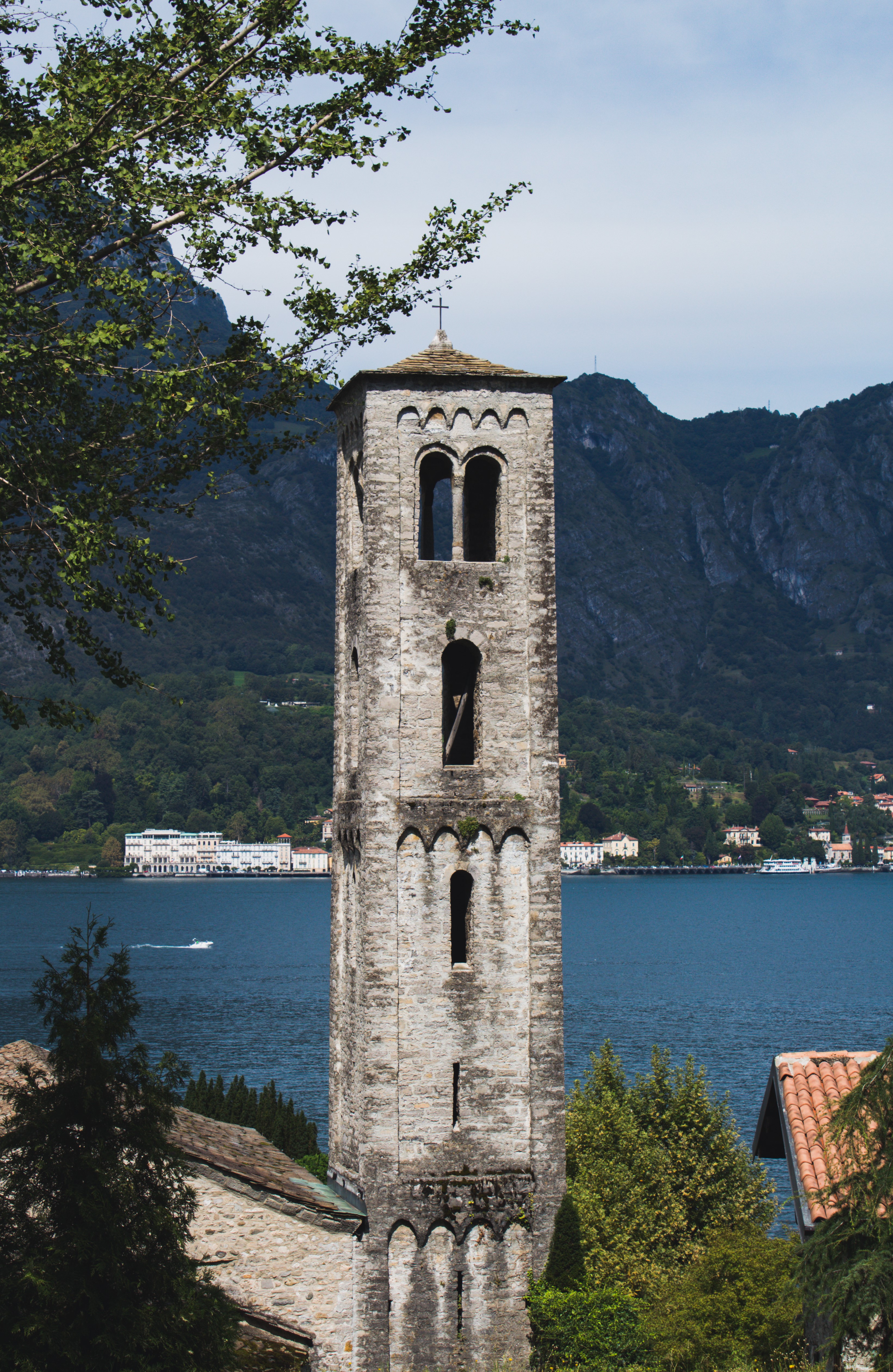 Bell tower by a lake with mountains in the background HD Phone Wallpaper