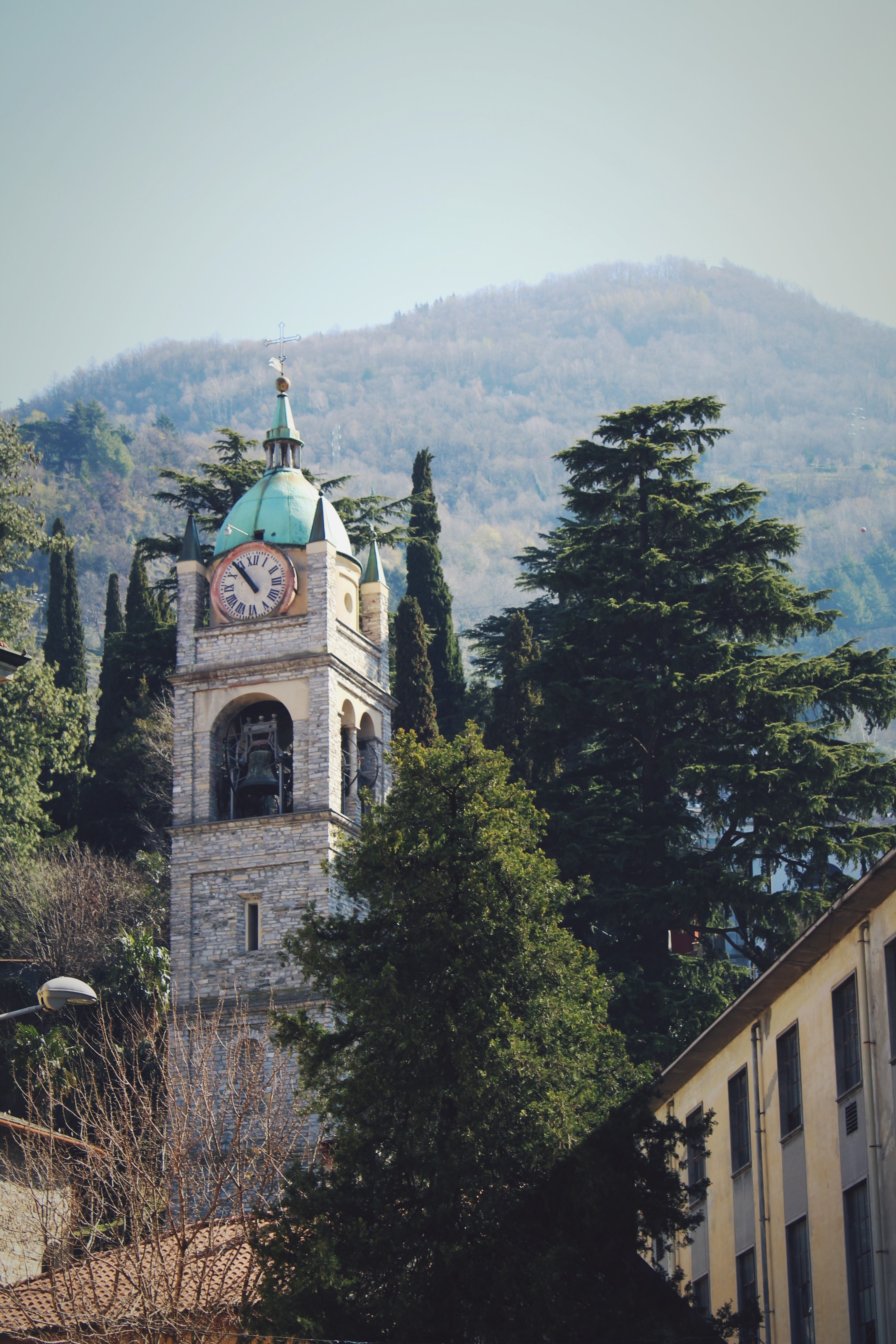 Bell tower with clock and mountains in background HD Phone Wallpaper