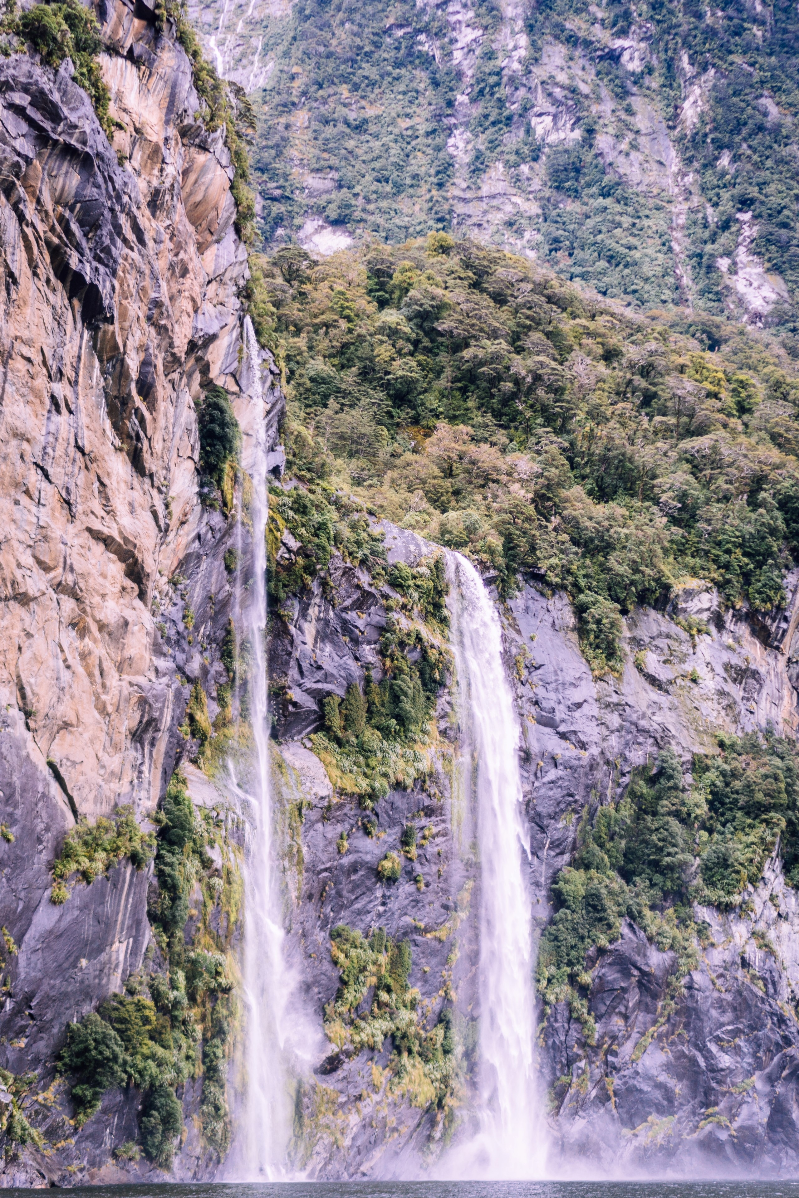 Waterfalls cascading down a rocky cliff face in New Zealand HD Phone Wallpaper
