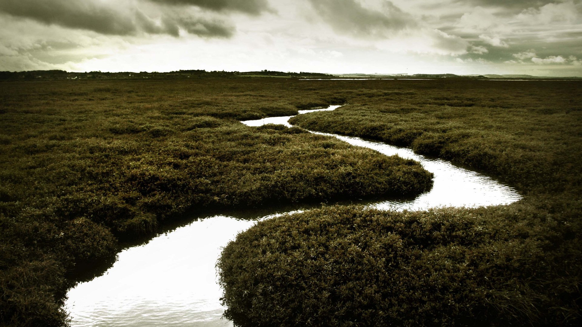 Winding river through marshland under cloudy sky HD Wallpaper
