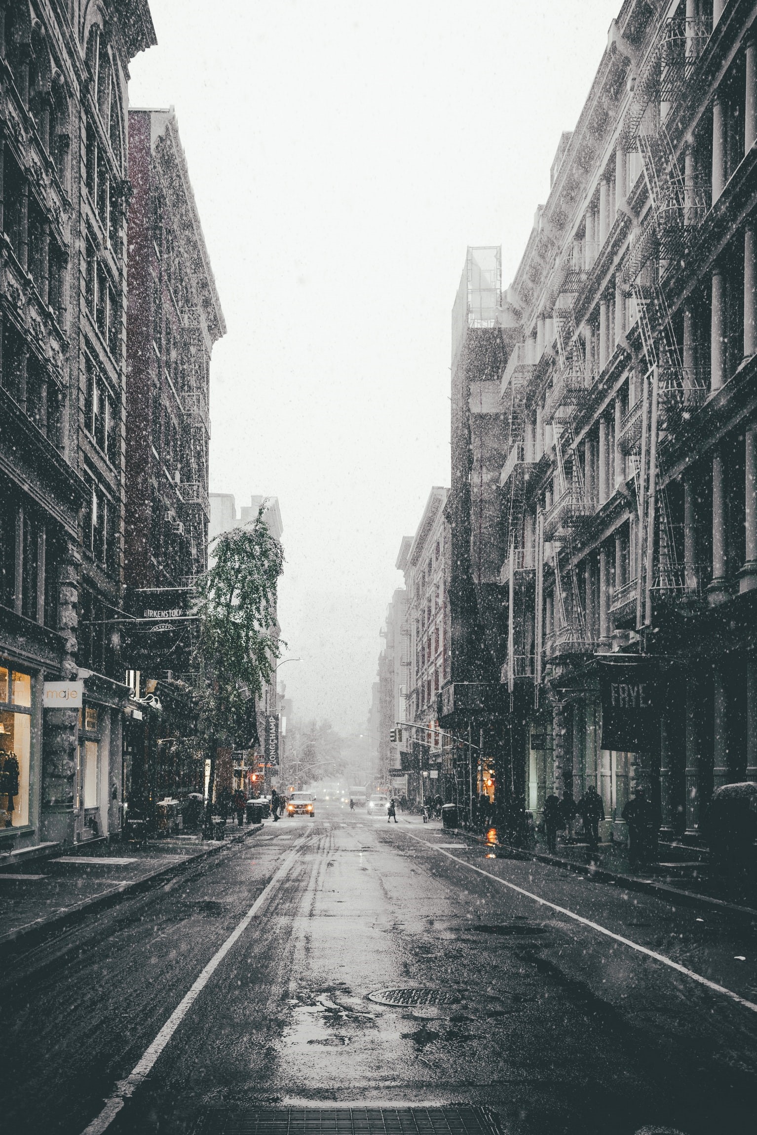 Snowy street in a city with tall buildings HD Phone Wallpaper