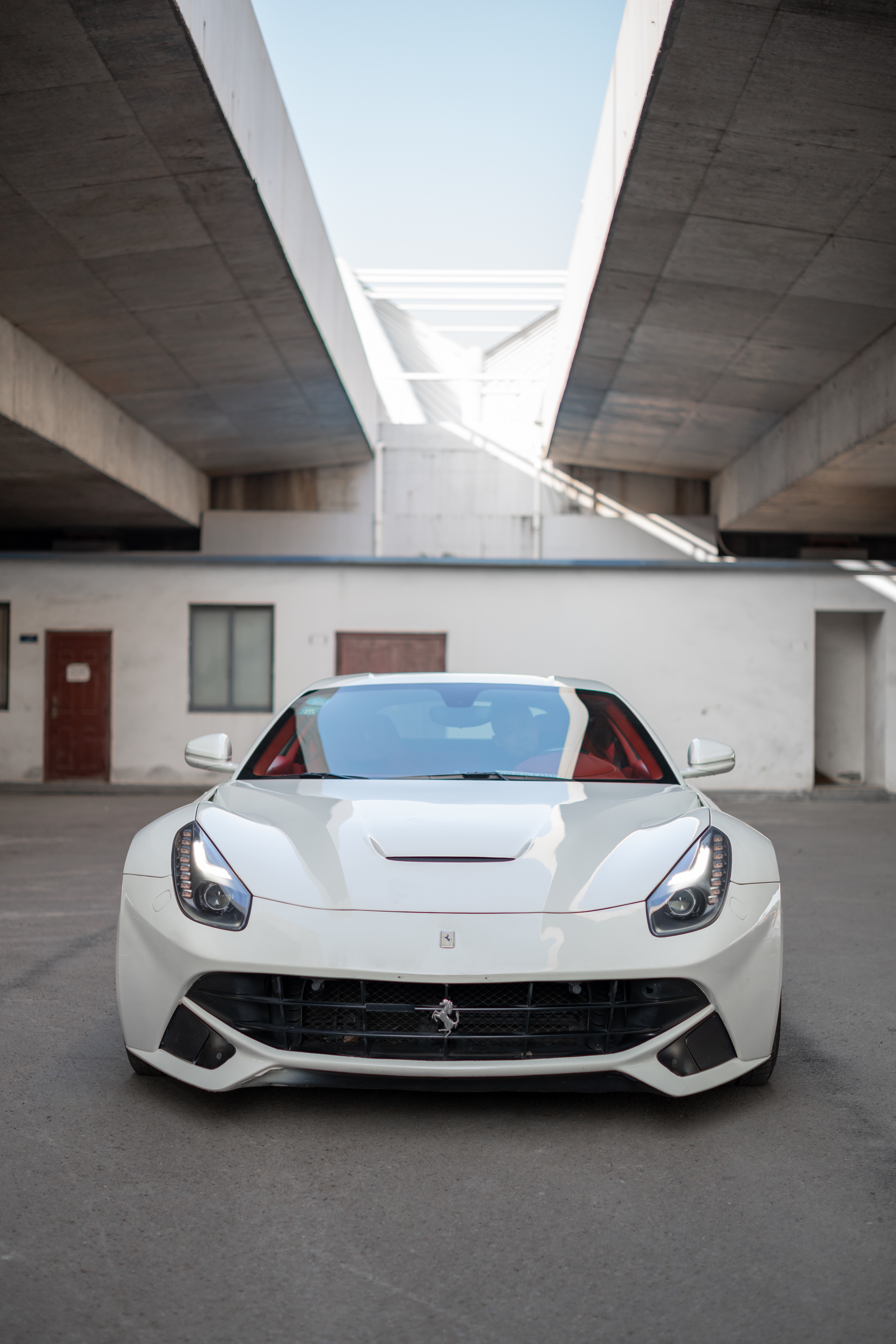 White Ferrari F12berlinetta parked under concrete structure HD Phone Wallpaper
