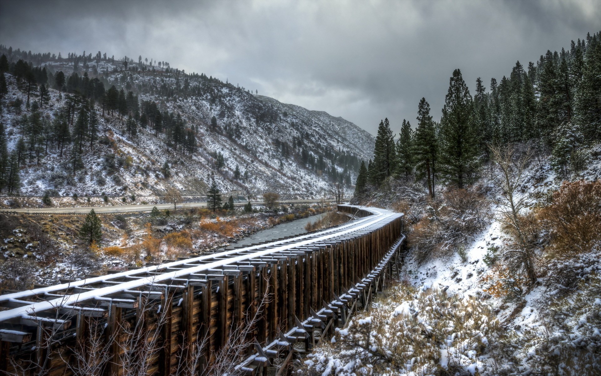 Wooden railroad bridge over a river in a snowy mountain landscape HD Wallpaper