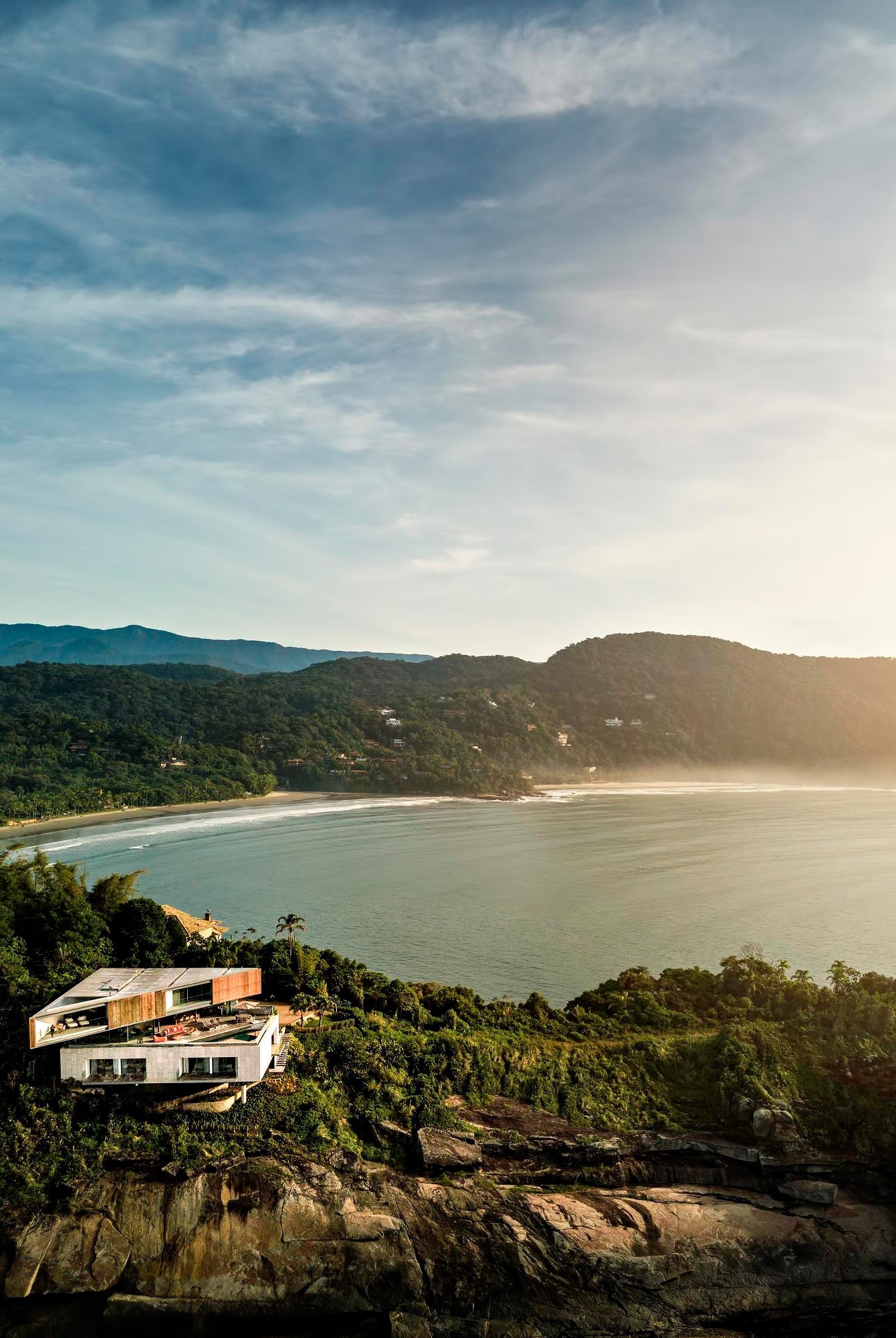 Modern house on a cliff overlooking a bay and mountains HD Phone Wallpaper