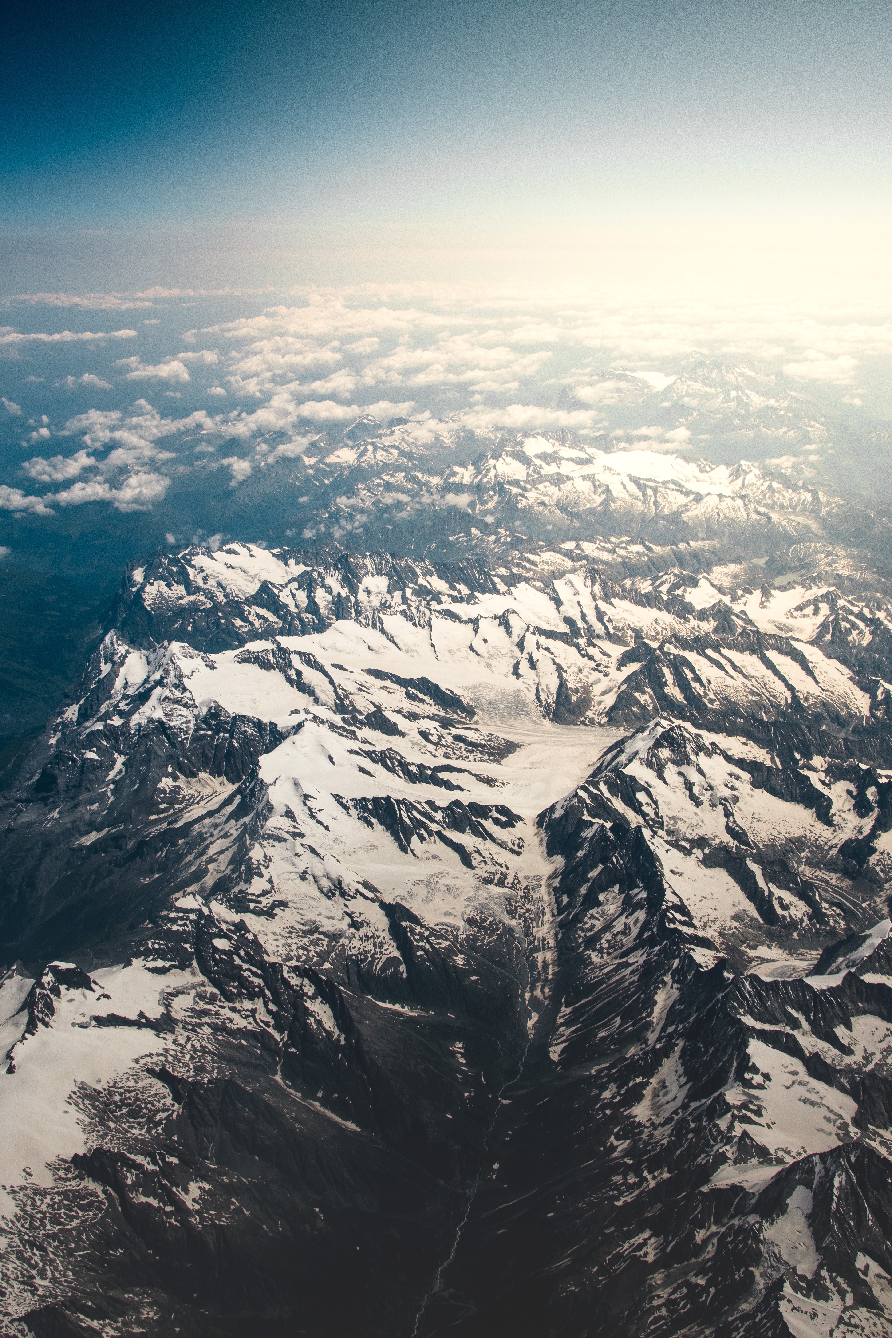Aerial view of snow-capped mountains and clouds HD Phone Wallpaper