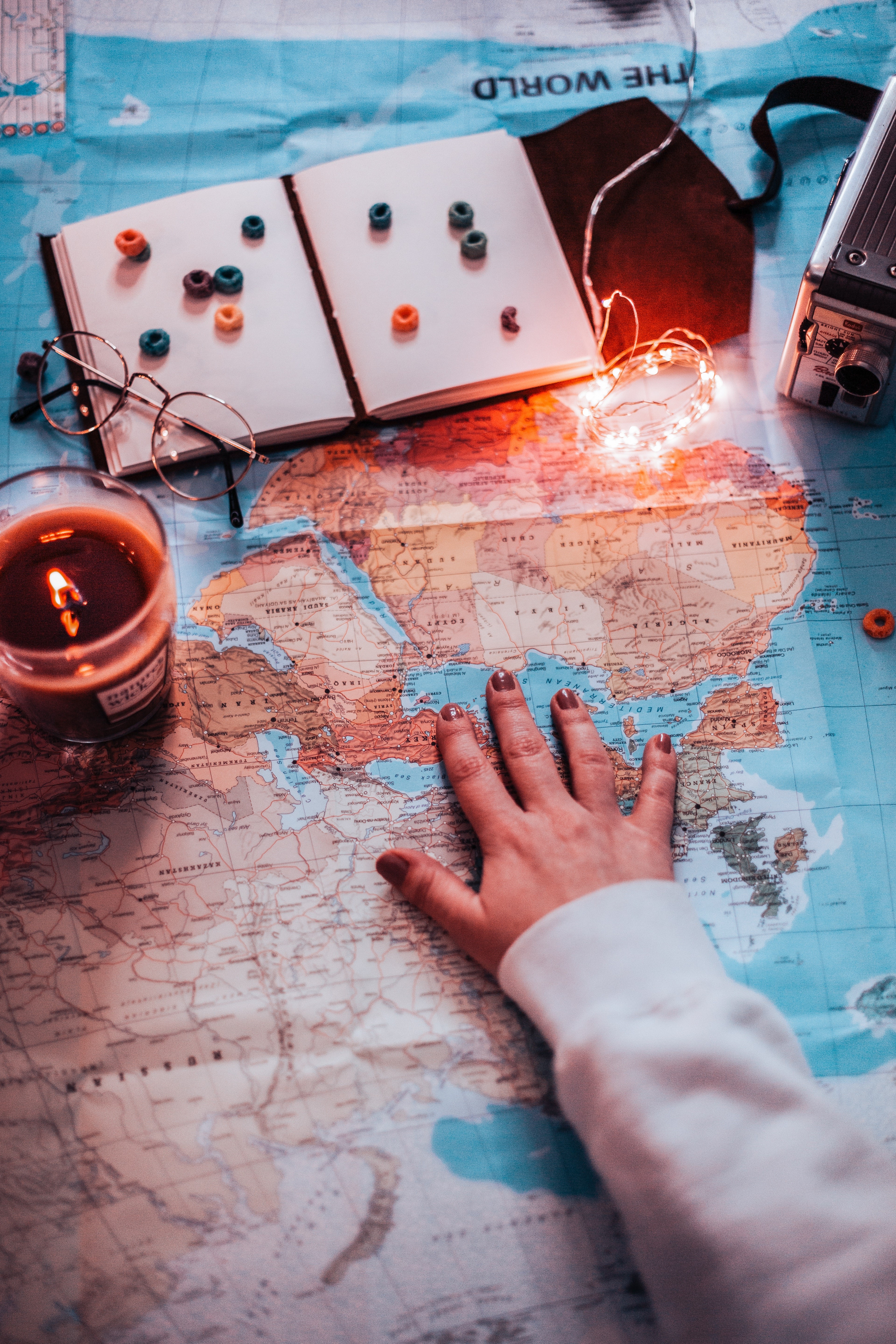 Hand on world map with travel items HD Phone Wallpaper