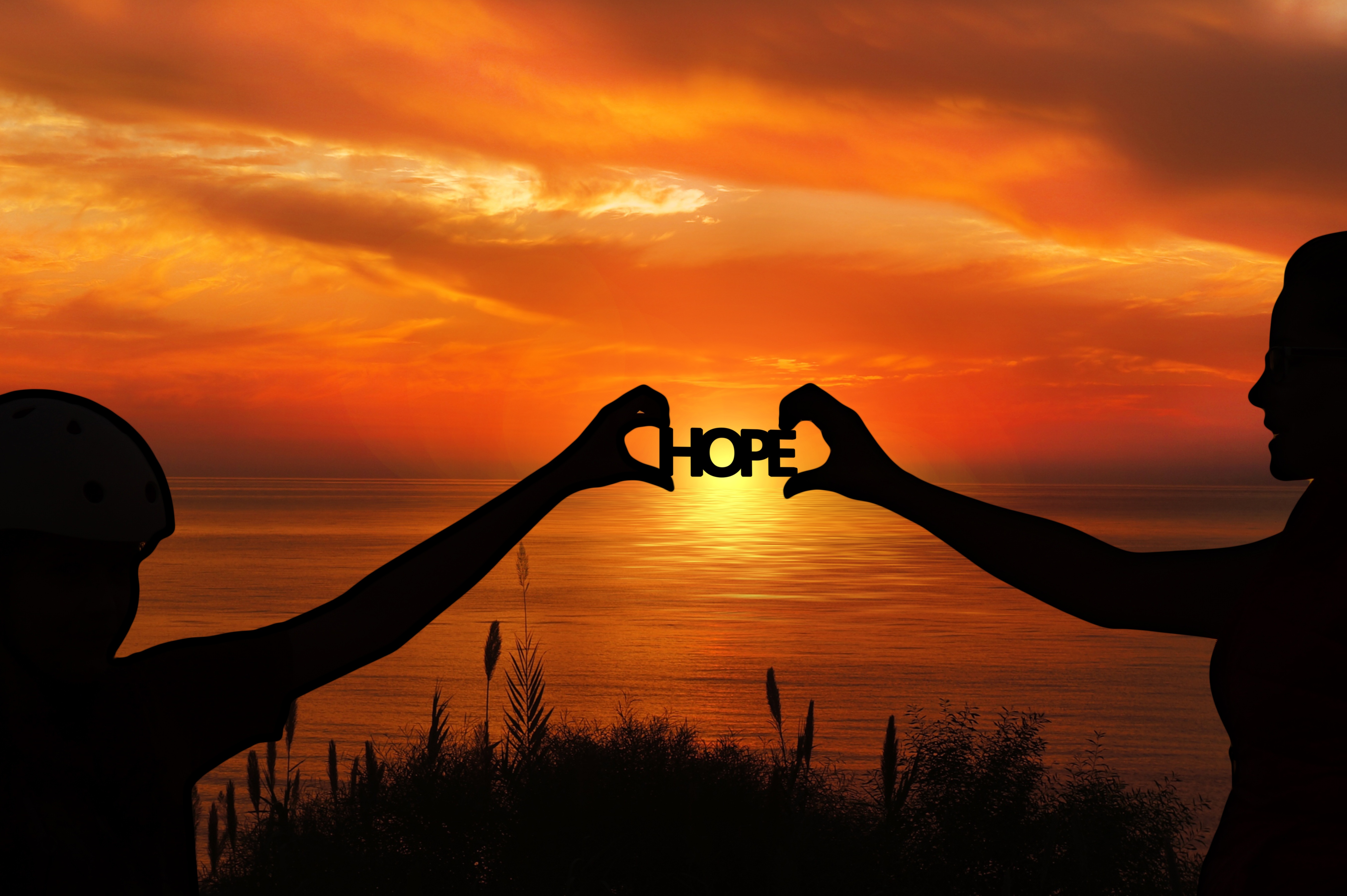 Silhouettes holding the word HOPE at sunset HD Wallpaper