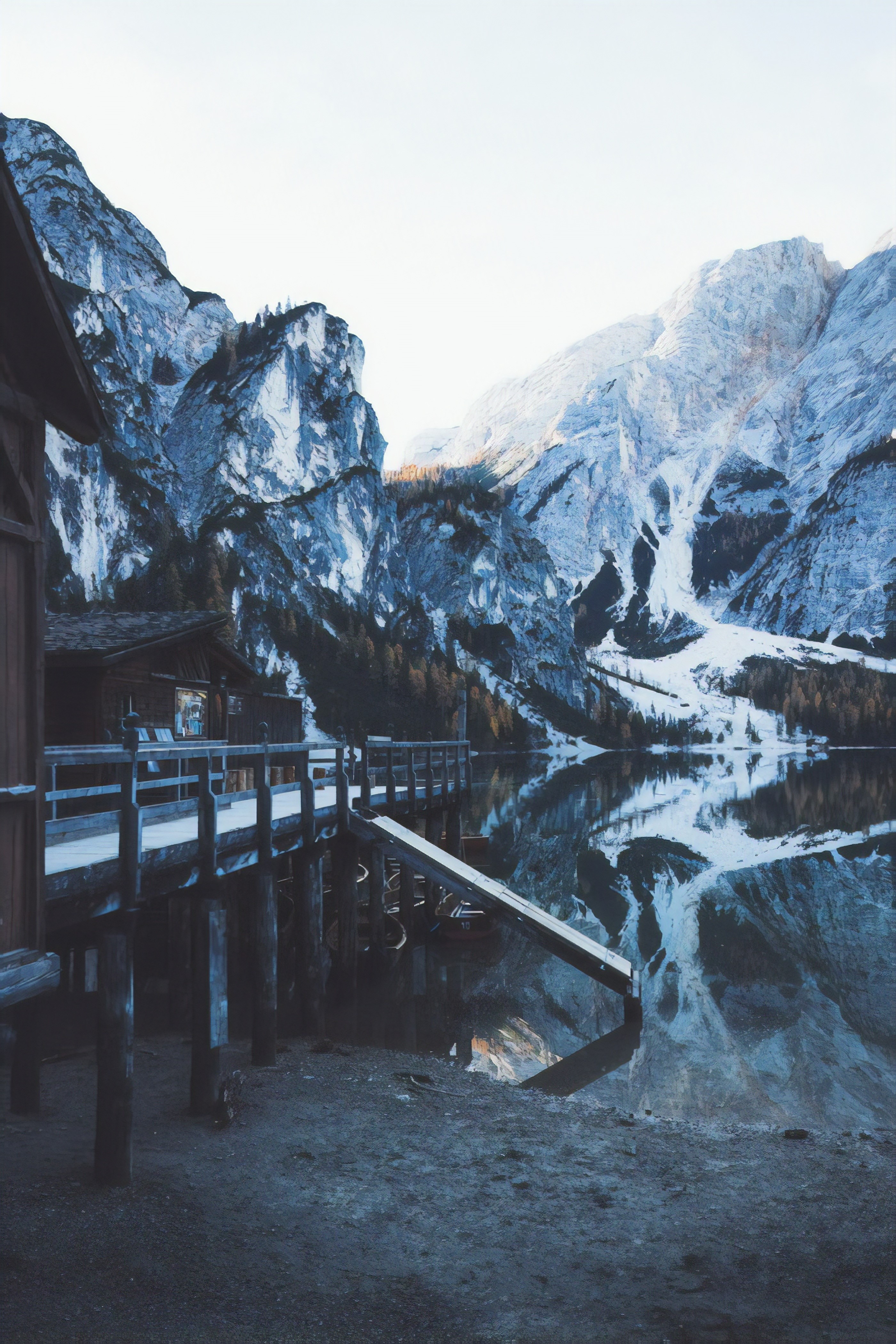 Wooden pier and cabin by a reflective mountain lake in winter HD Phone Wallpaper