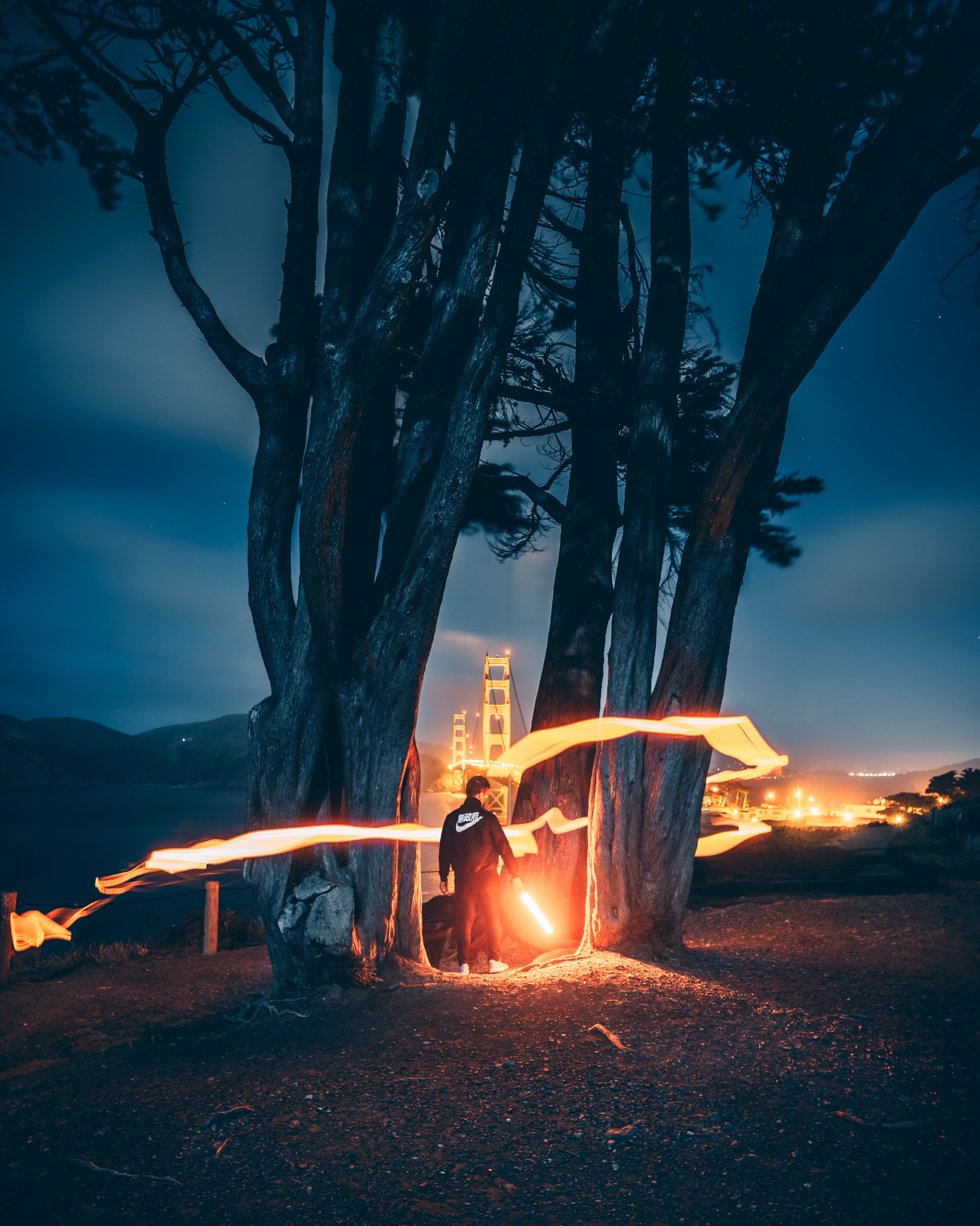 Man with Lightsaber and Light Trails near Golden Gate Bridge HD Phone Wallpaper