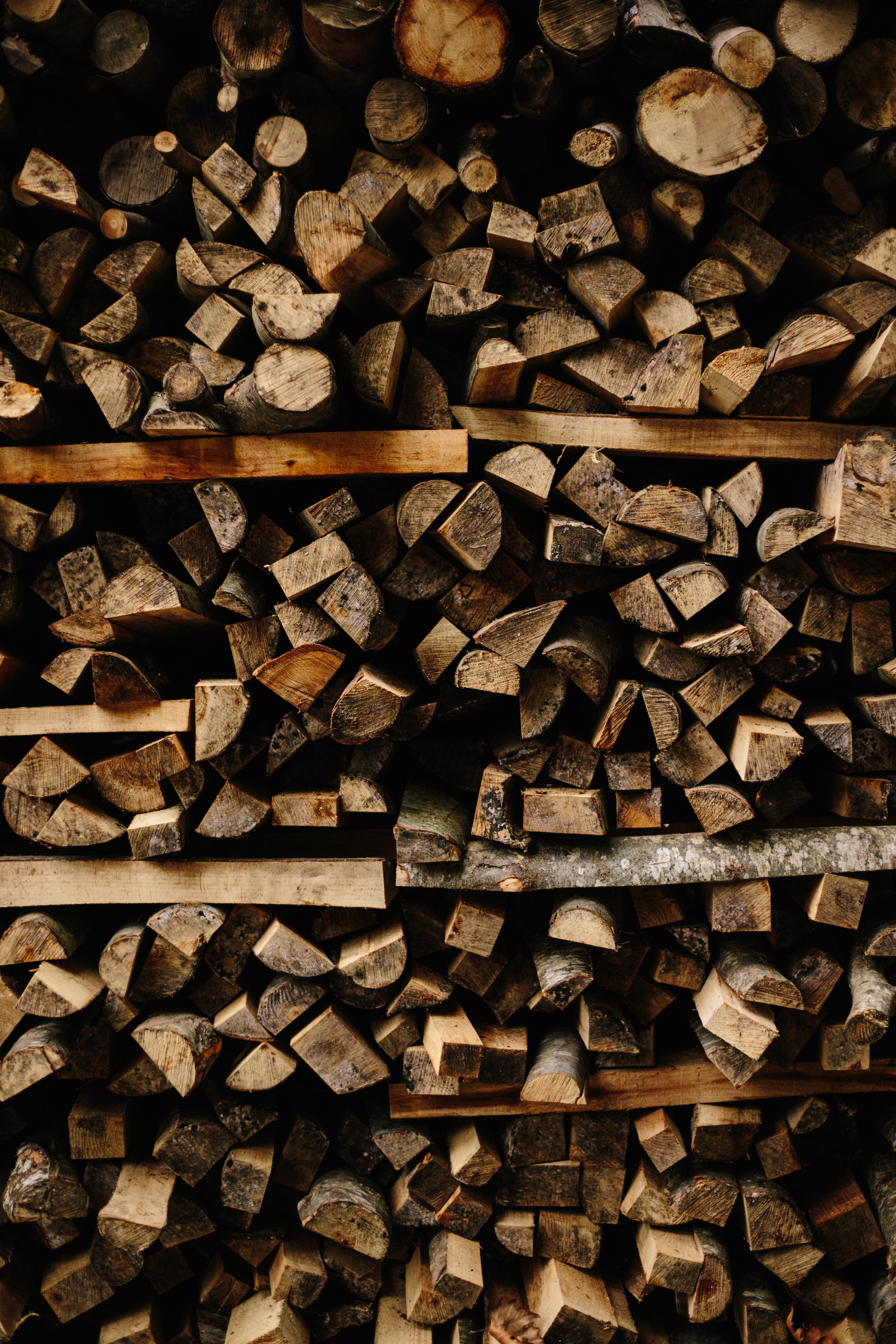 Pile of chopped firewood stacked on wooden shelves HD Phone Wallpaper