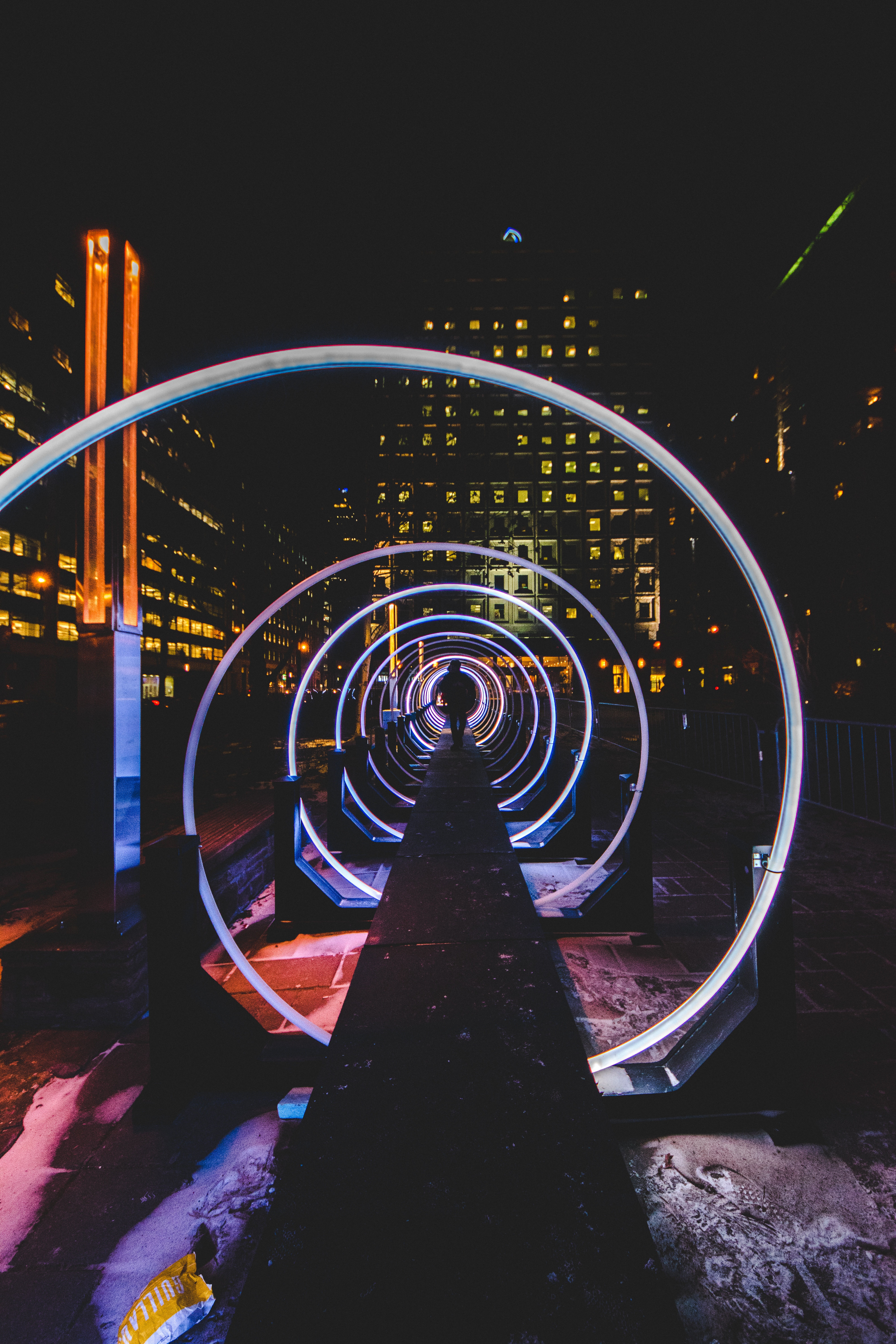 Man walking through a neon spiral tunnel at night HD Wallpaper