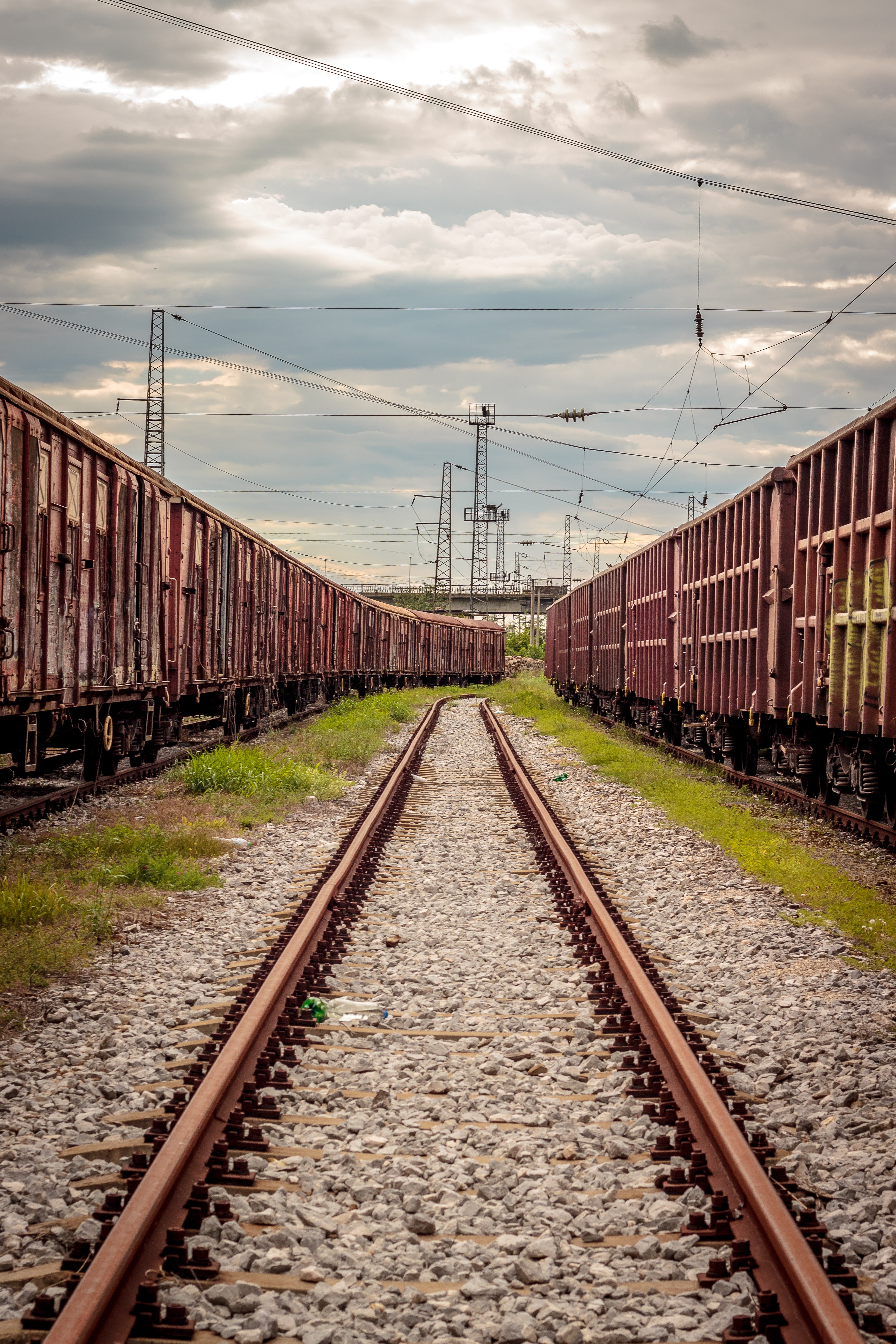 Freight trains on railway tracks under cloudy sky HD Phone Wallpaper