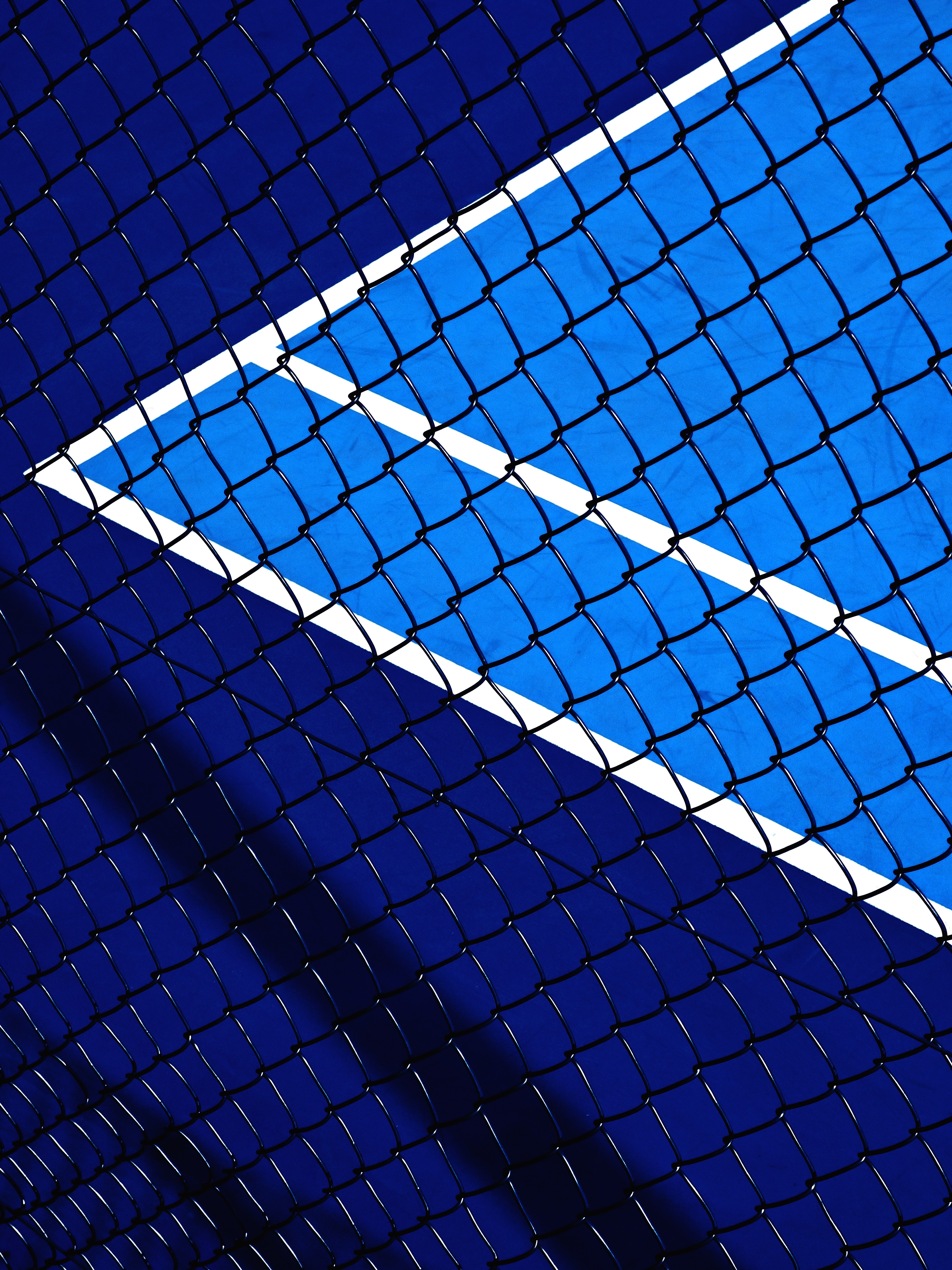 Blue tennis court behind a fence HD Phone Wallpaper