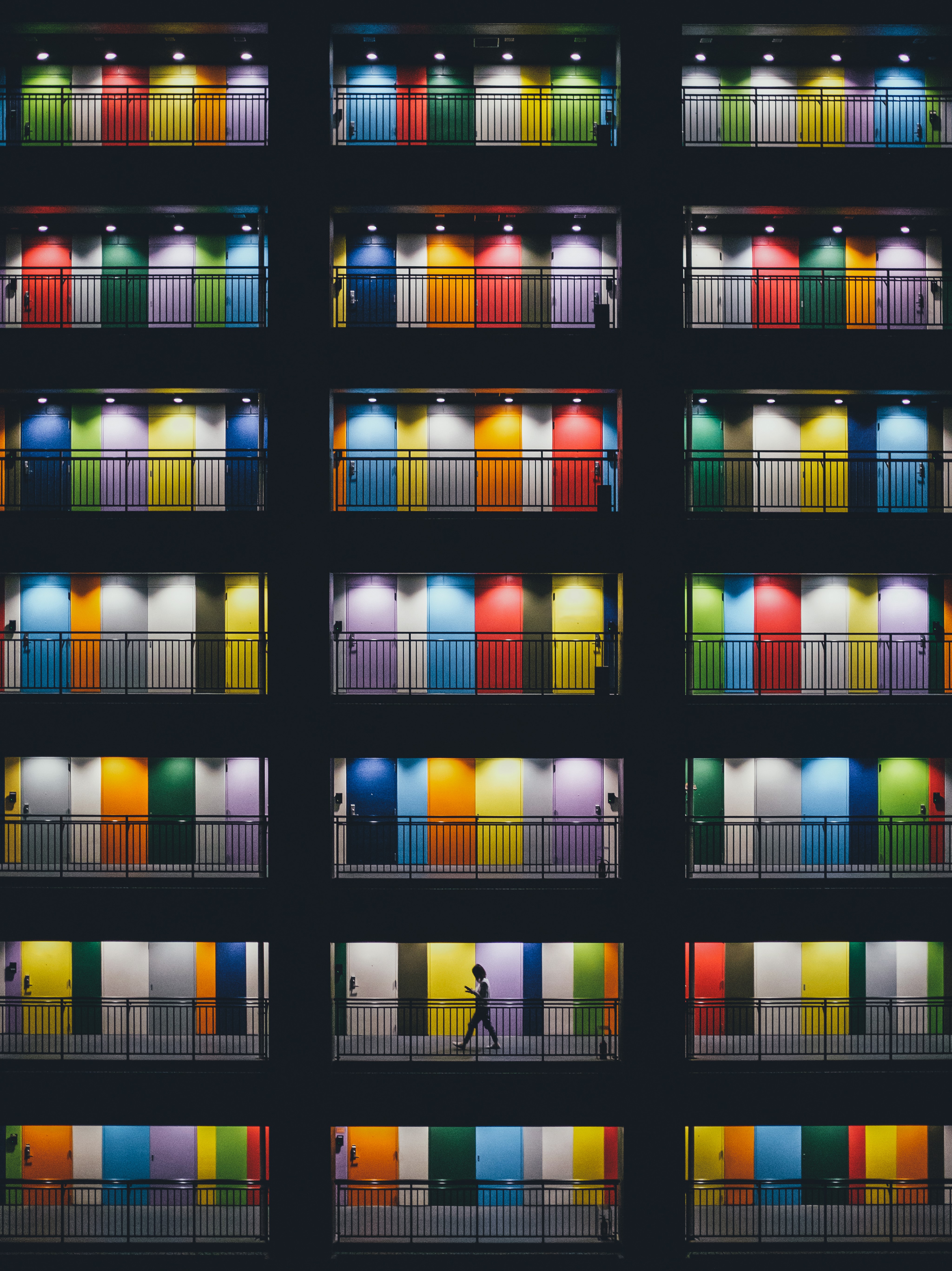 Colorful doors and balconies at night with a person walking HD Phone Wallpaper