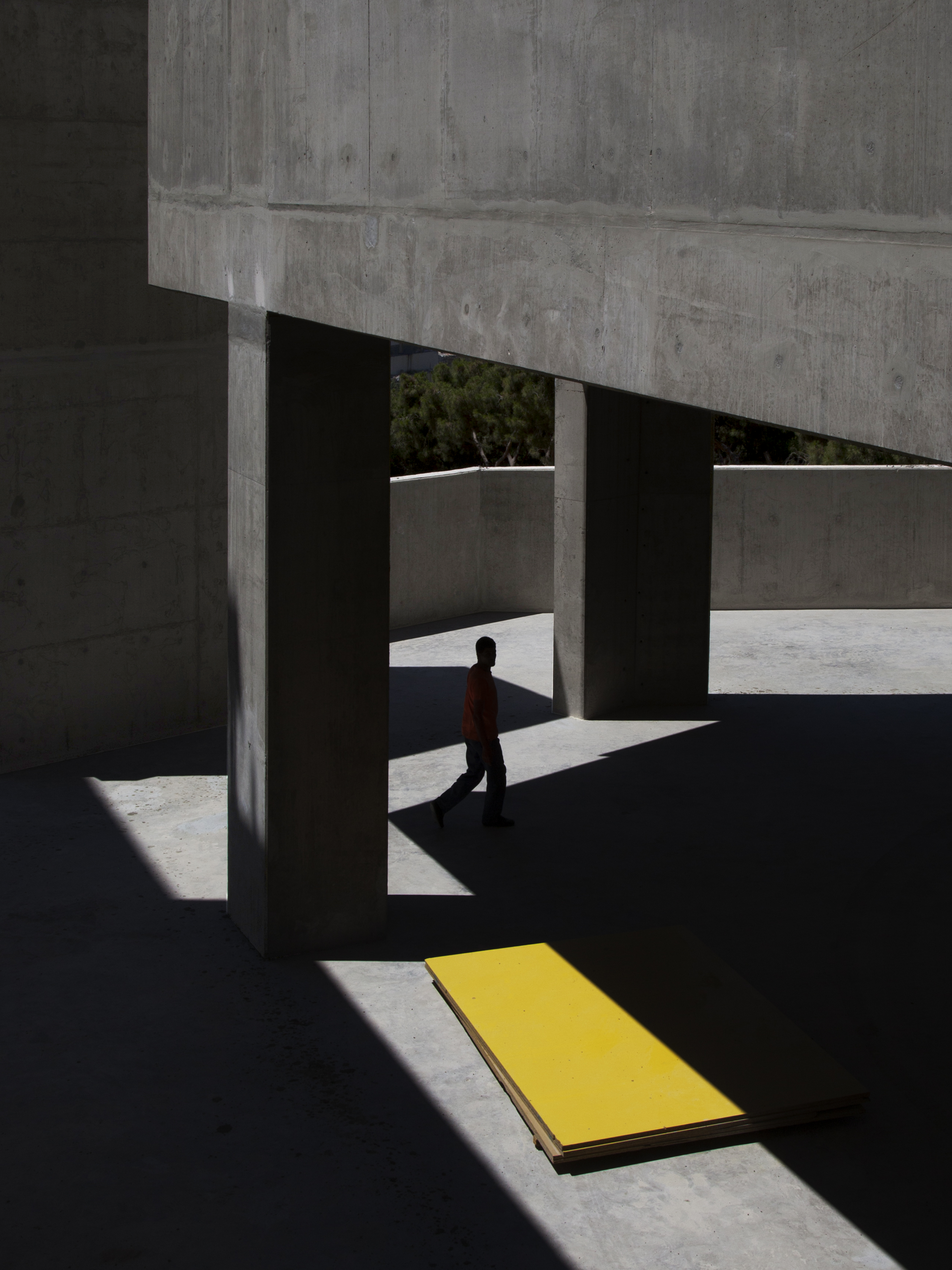 Man walking near concrete pillars and yellow board HD Phone Wallpaper