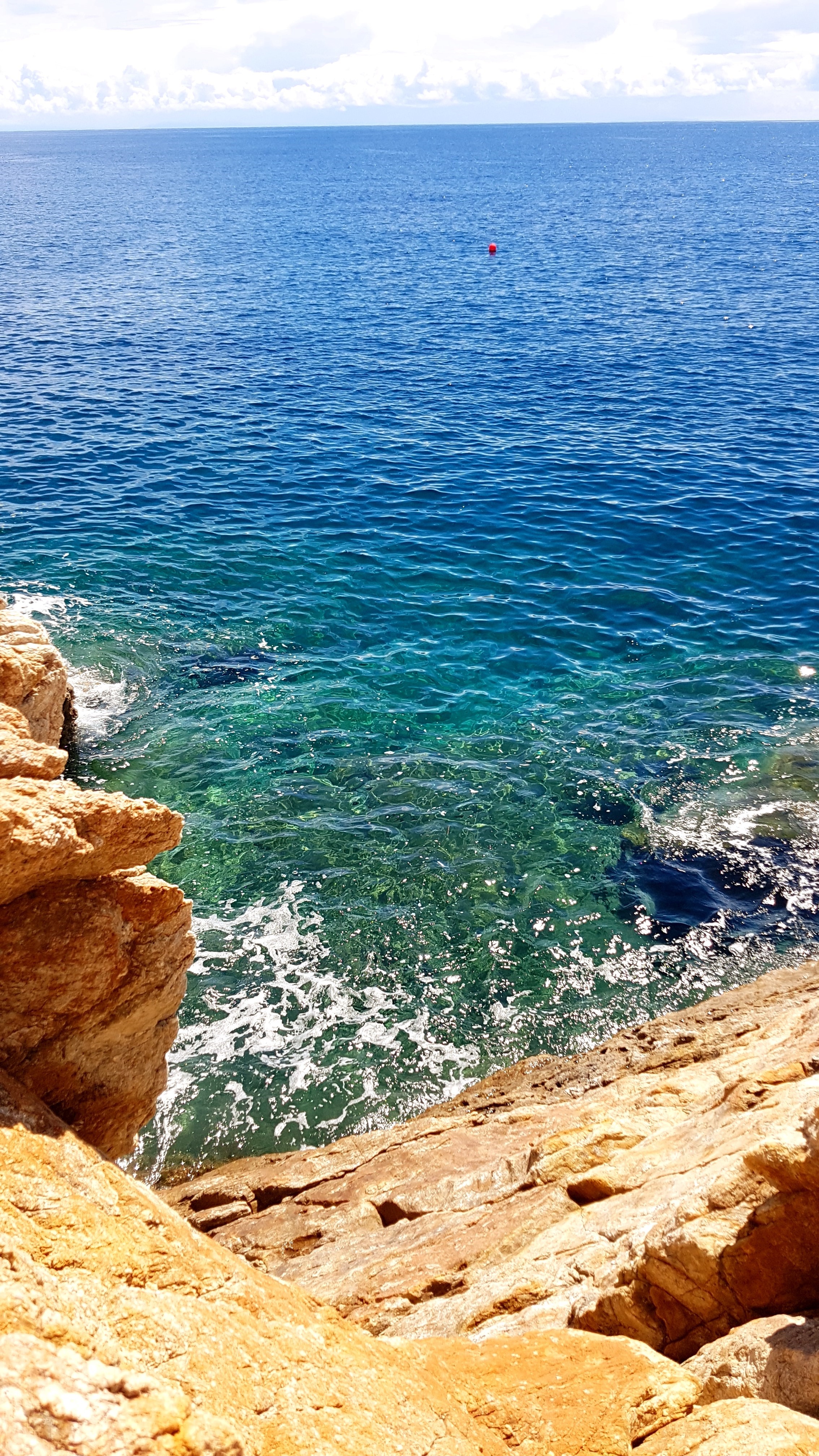 Rocky coast overlooking clear blue sea with a buoy HD Phone Wallpaper