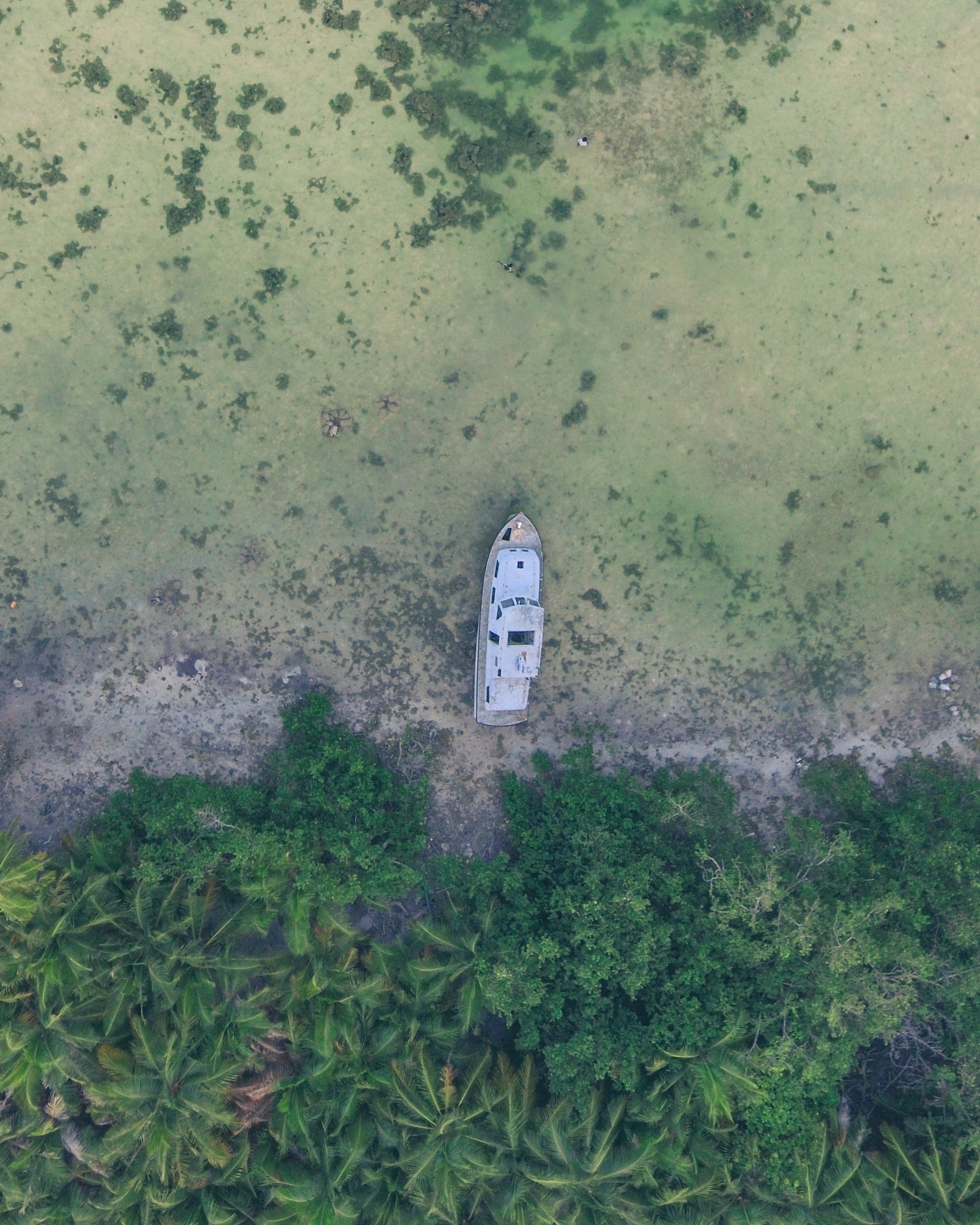 Aerial view of a beached boat near a tropical coastline HD Phone Wallpaper