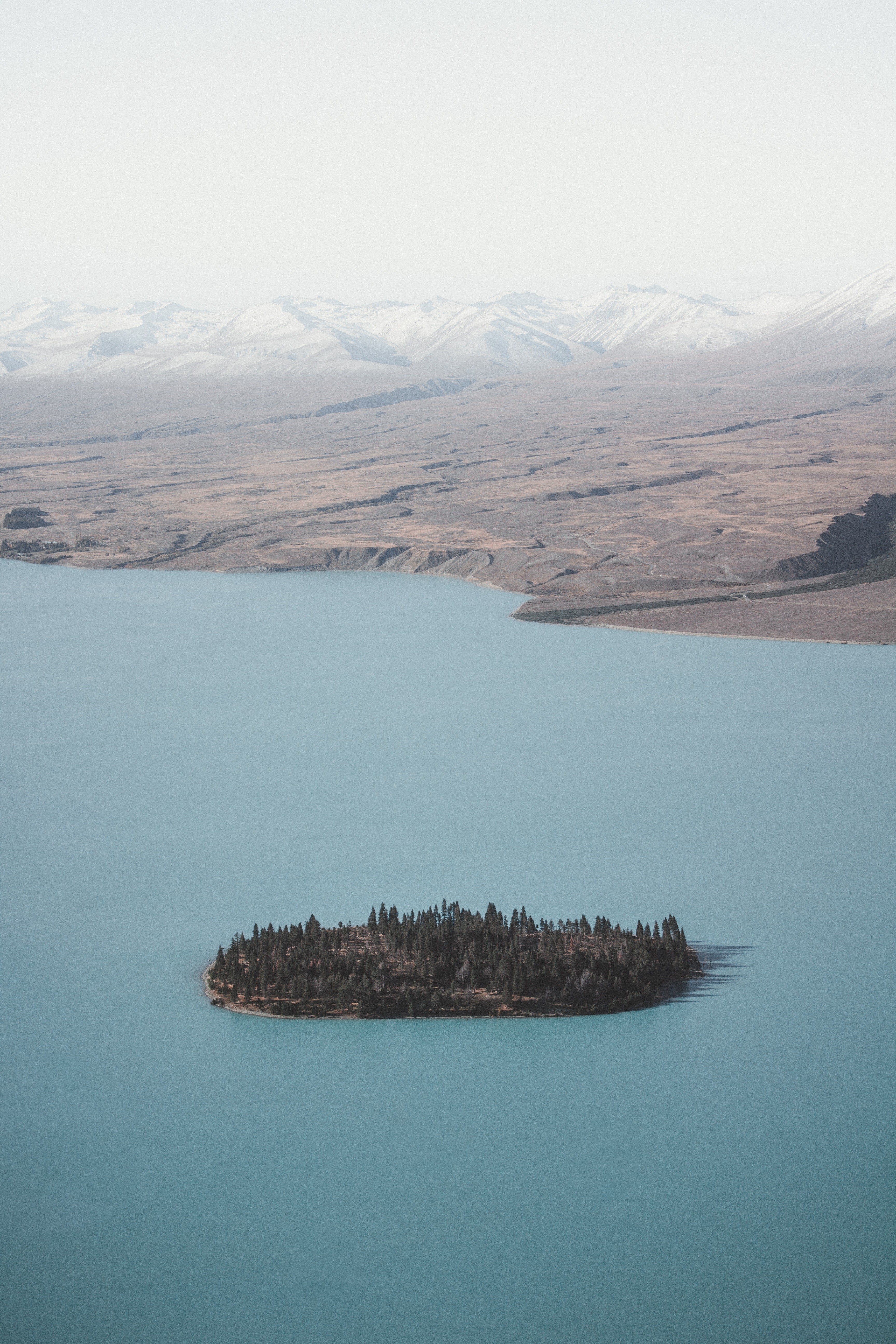 Island with trees in a lake with mountains in the background HD Phone Wallpaper