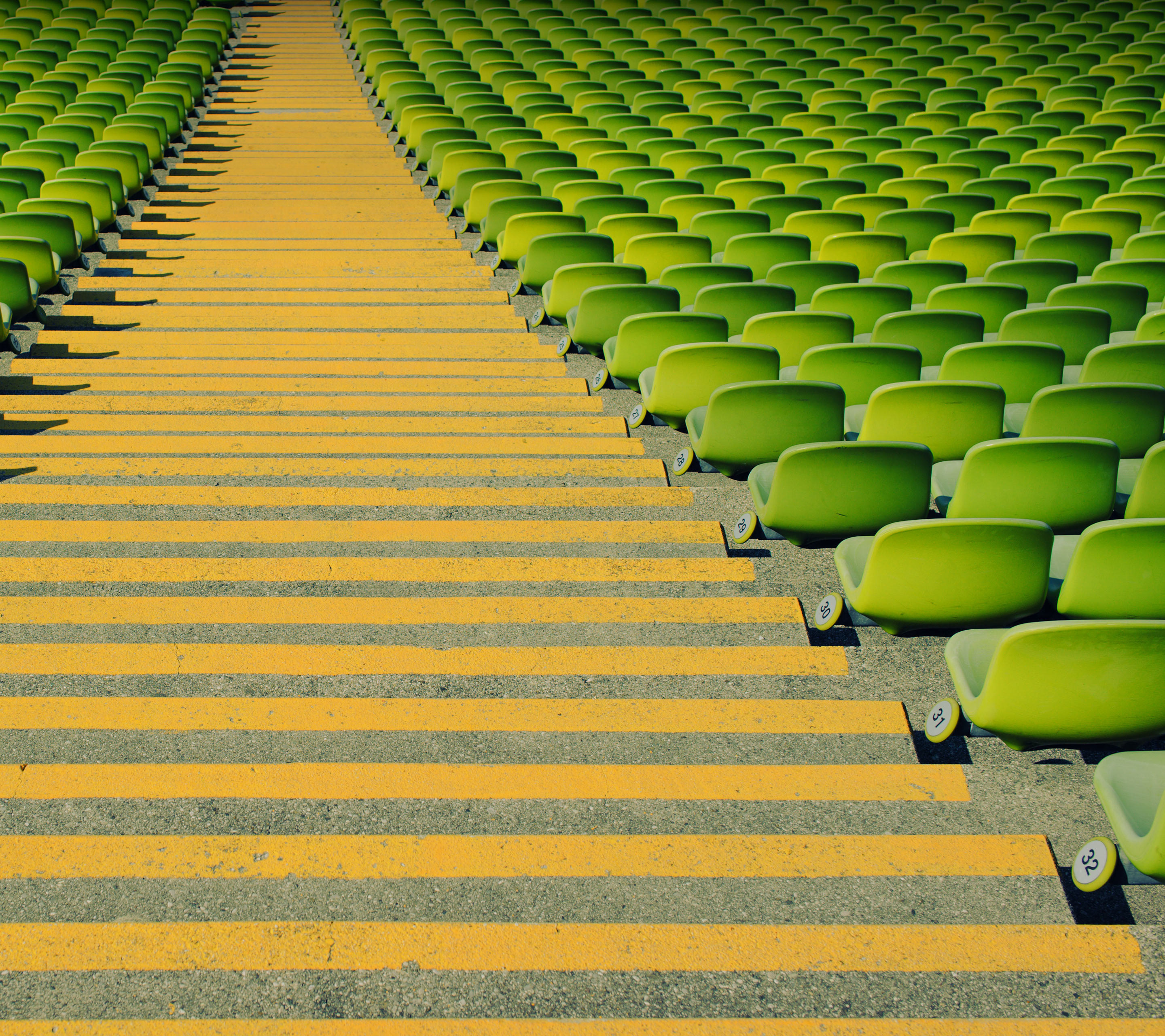 Rows of green stadium seats with yellow striped steps HD Wallpaper