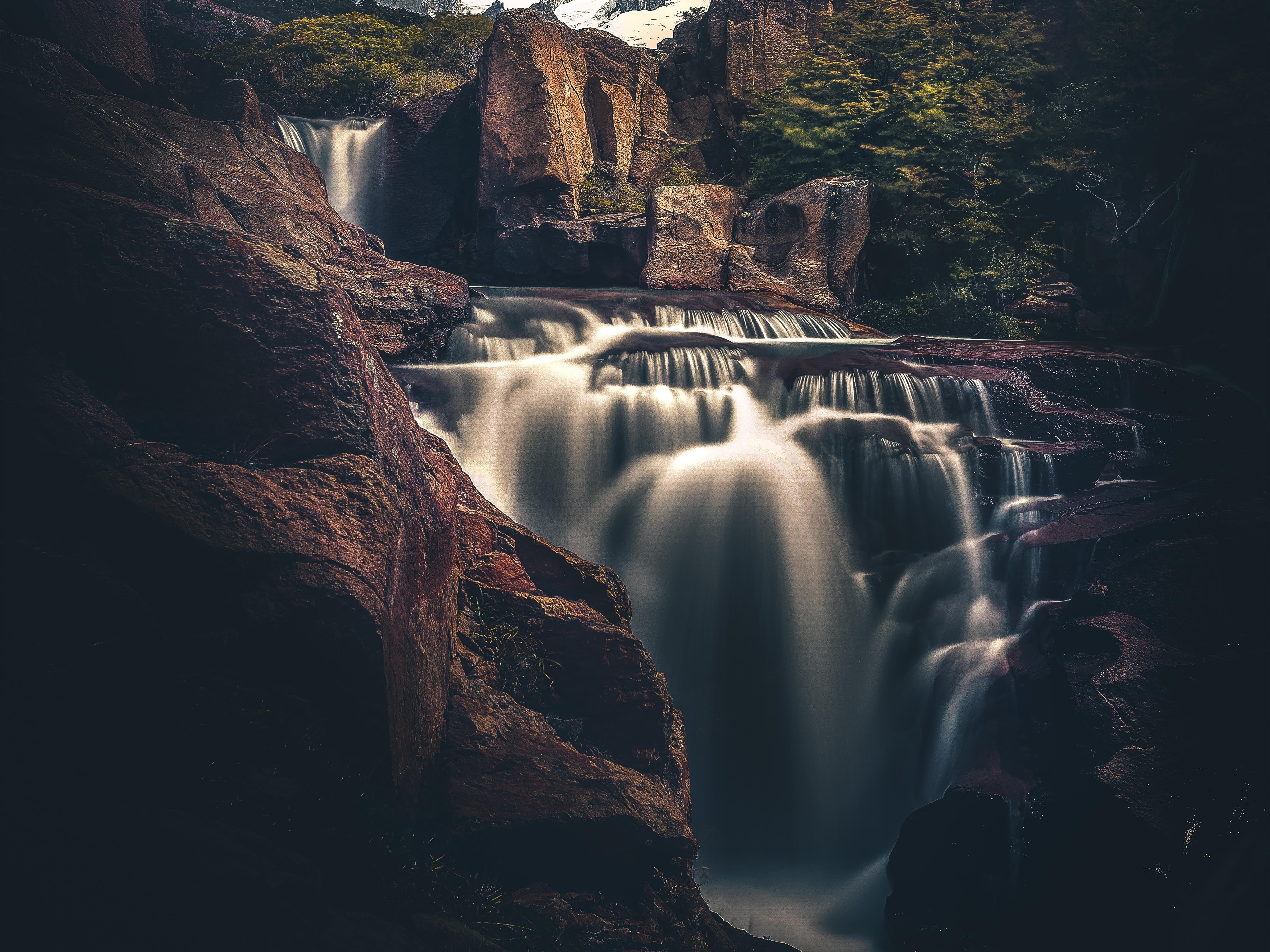 Waterfall cascading over rocks in a forest HD Wallpaper