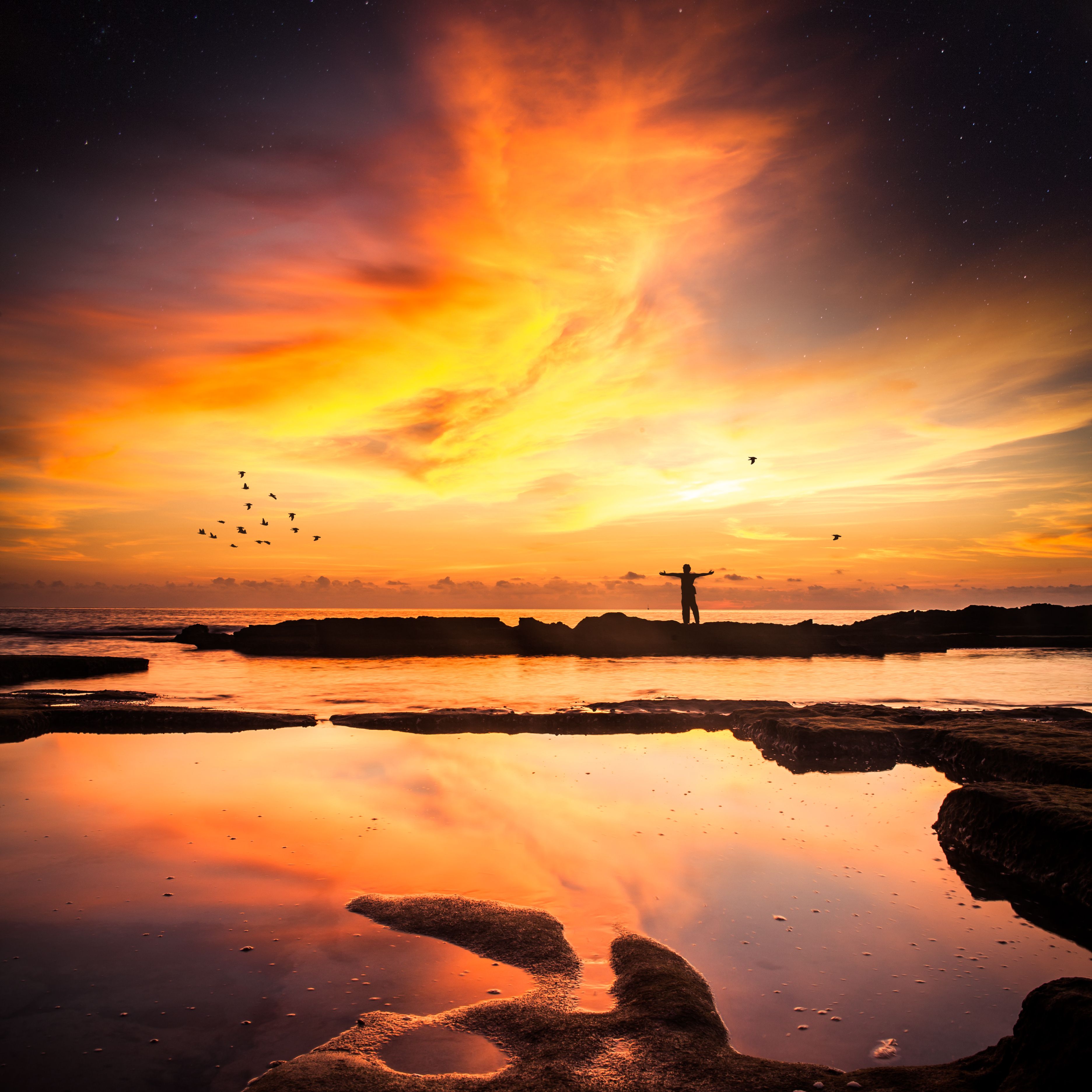 Silhouette of a person with arms outstretched at sunset with reflections HD Wallpaper