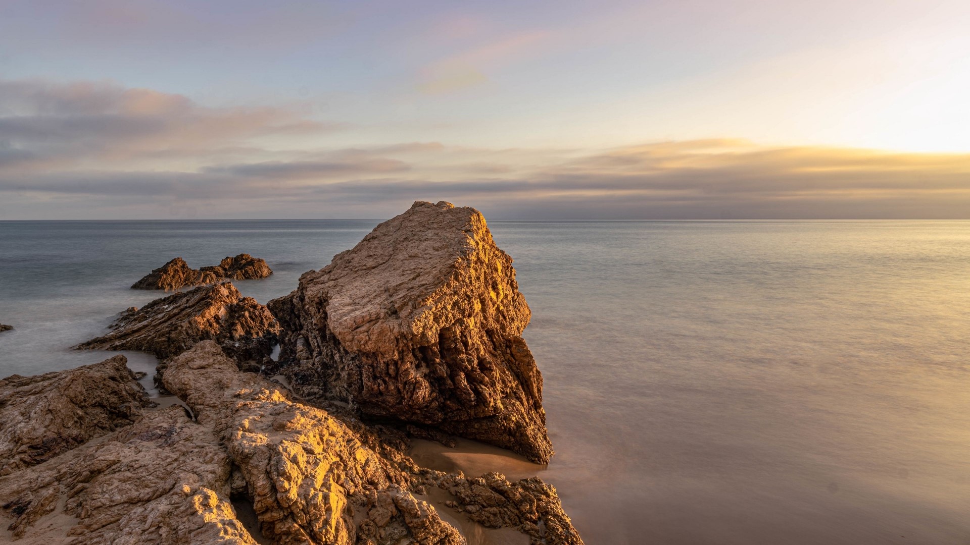 Rocks on a beach at sunset HD Wallpaper
