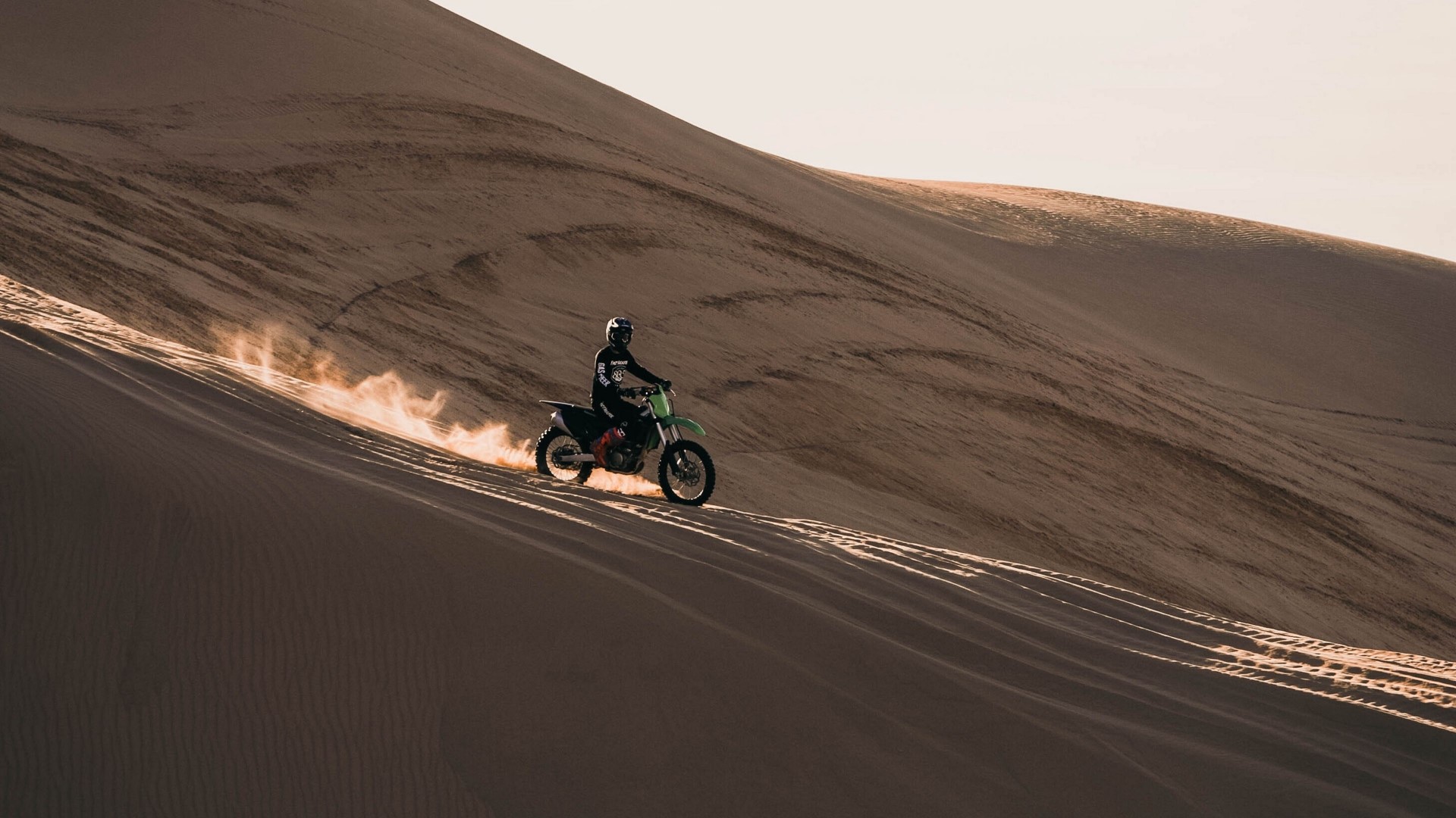 Motorcyclist riding on a sand dune HD Wallpaper