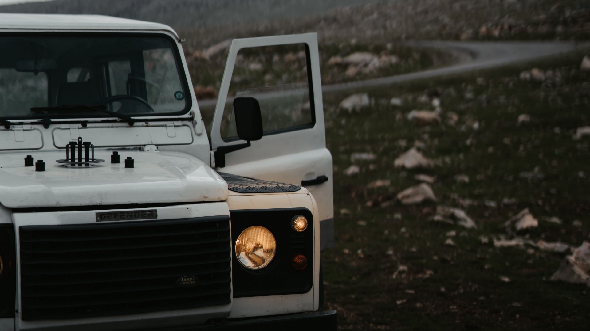 White Land Rover Defender parked on a rocky hill HD Wallpaper