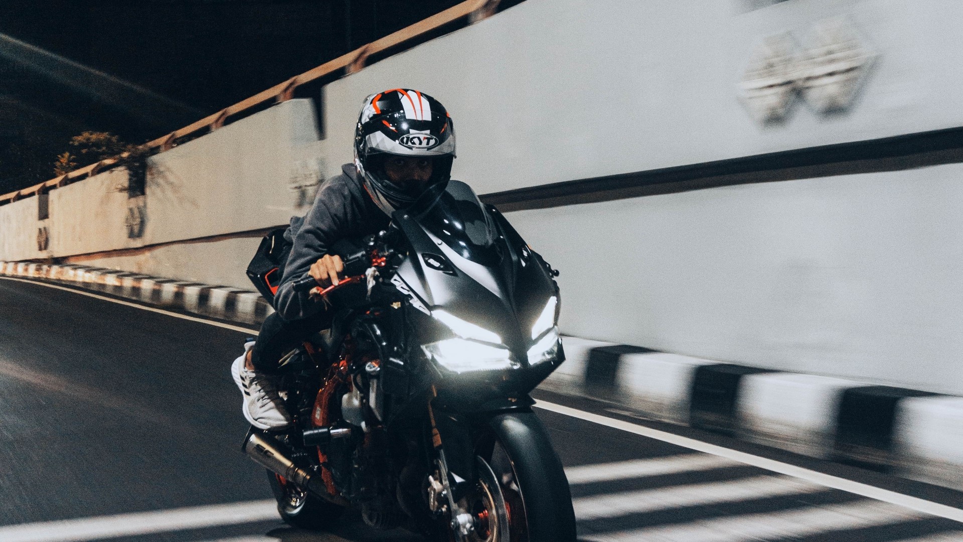 Motorcyclist wearing a helmet riding a sportbike at night HD Wallpaper