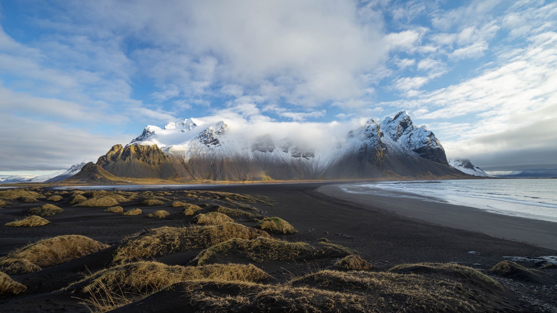Snow-capped mountains on a black sand beach HD Wallpaper