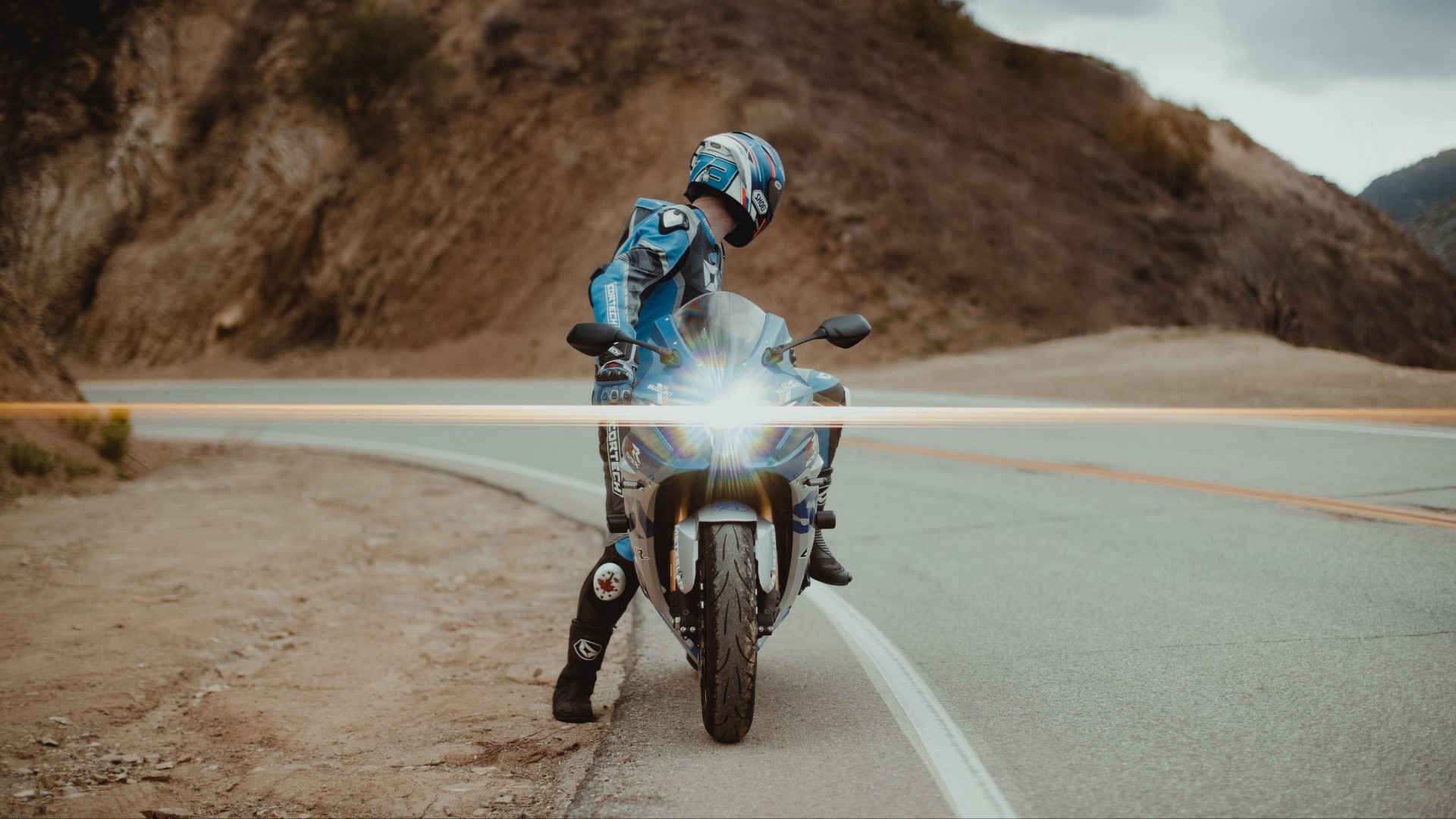 Motorcyclist in blue gear on a motorcycle on a road HD Wallpaper