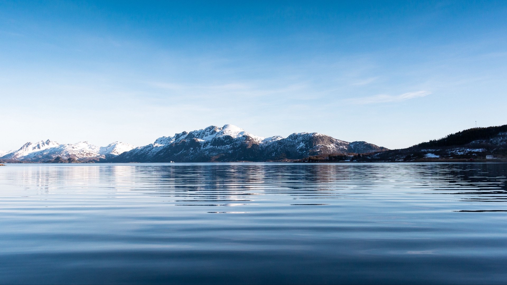 Snow-capped mountains reflected in calm water under a blue sky HD Wallpaper