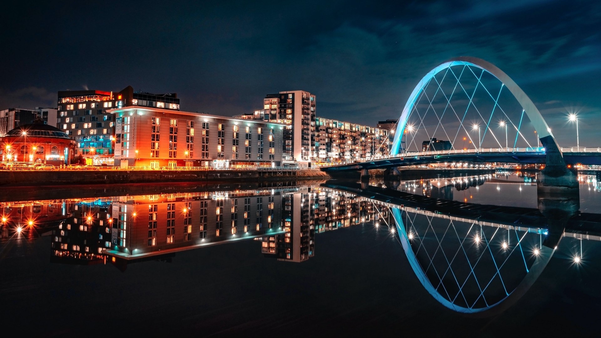 Night cityscape with illuminated bridge and buildings reflected in water HD Wallpaper