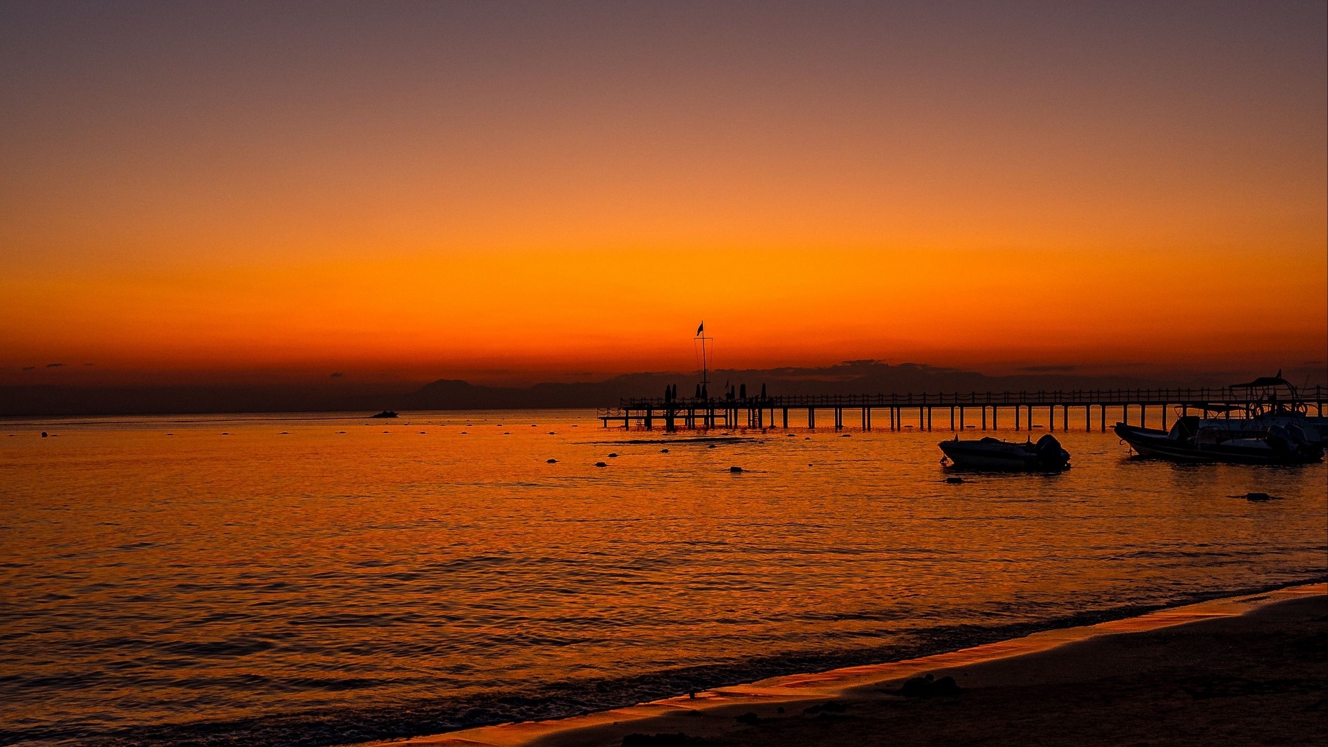 Sunset over the ocean with a pier and boats HD Wallpaper