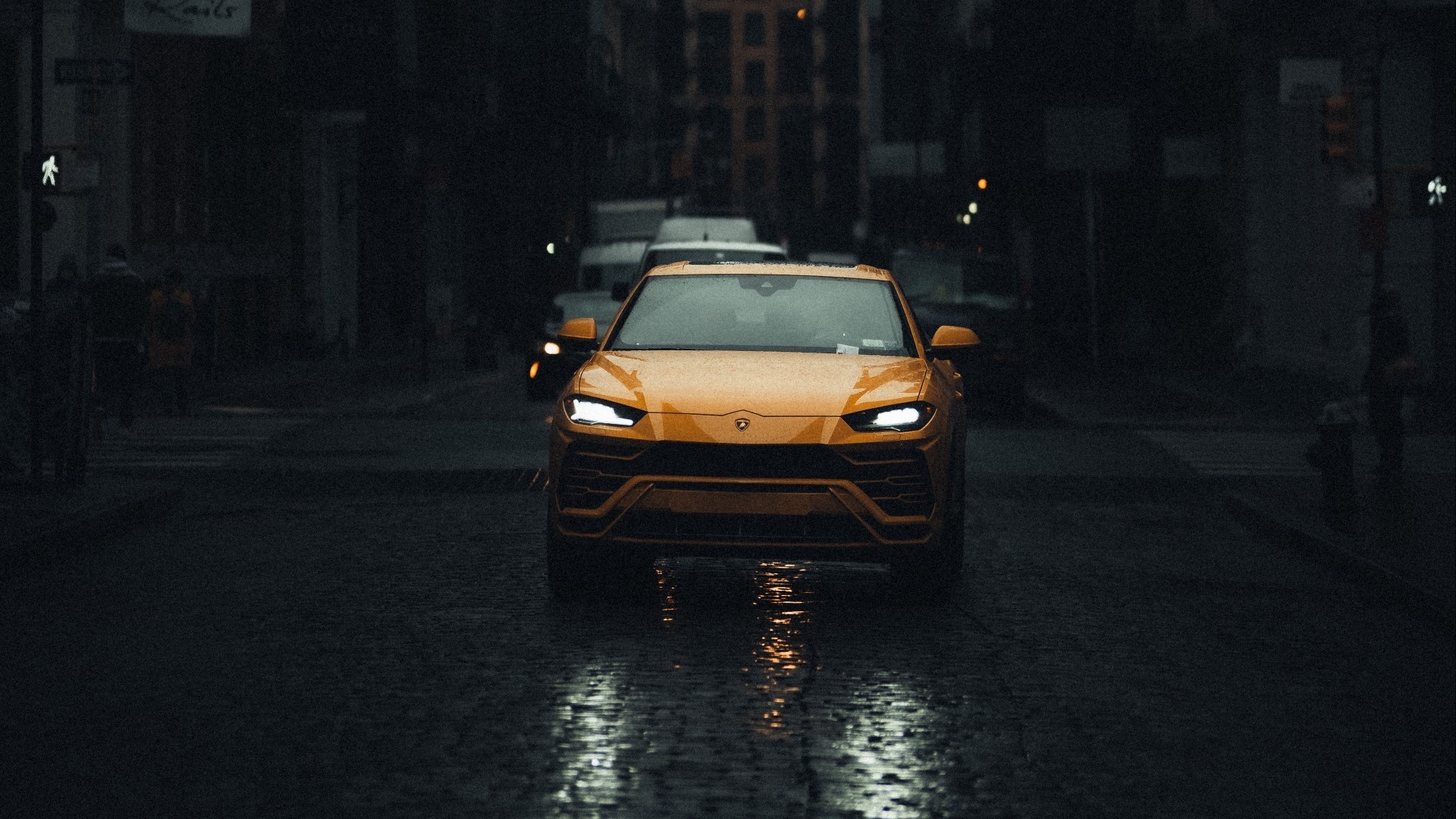 Yellow Lamborghini Urus driving on wet city street HD Wallpaper