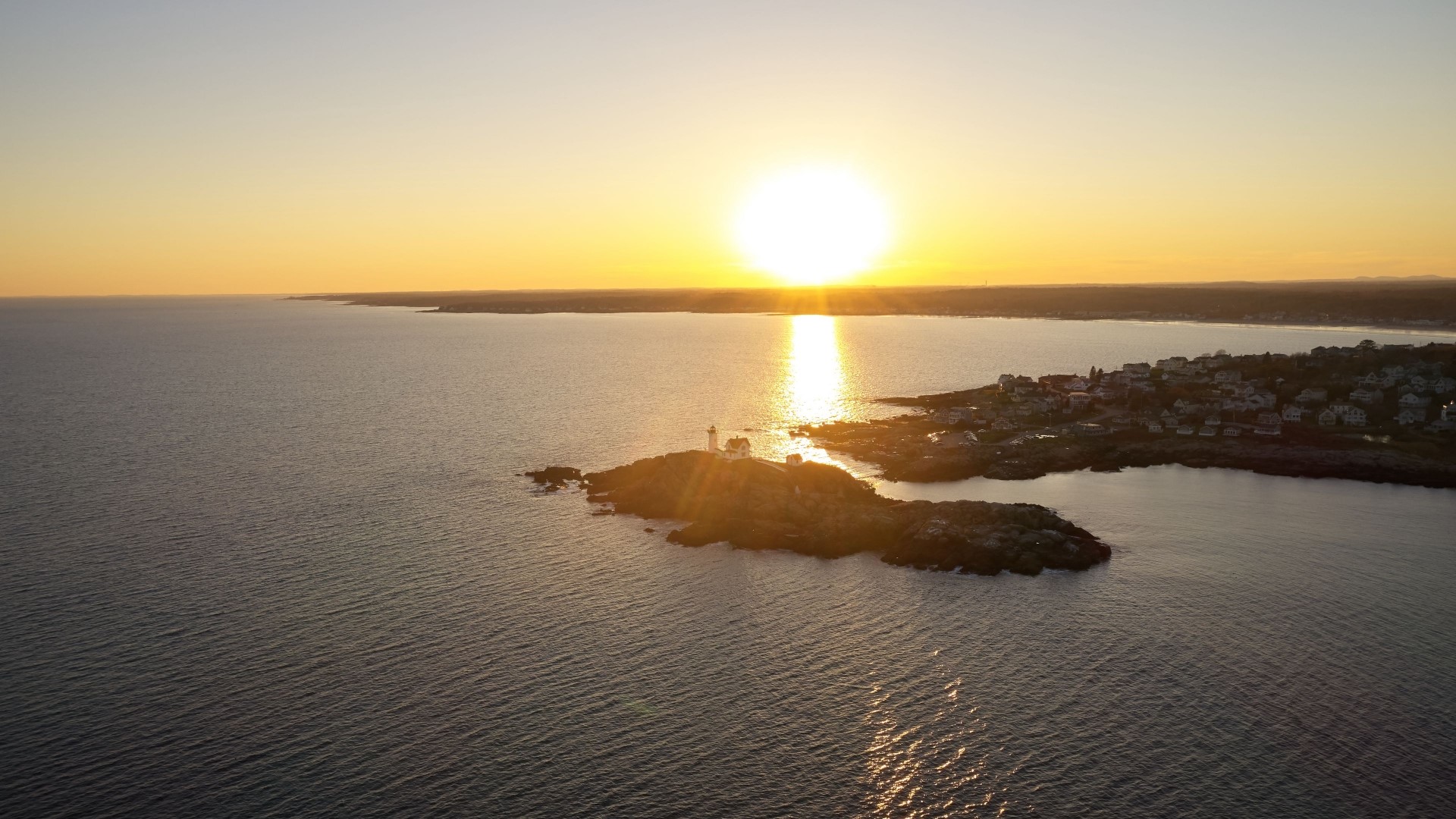 Sunset over a coastal town with a lighthouse HD Wallpaper