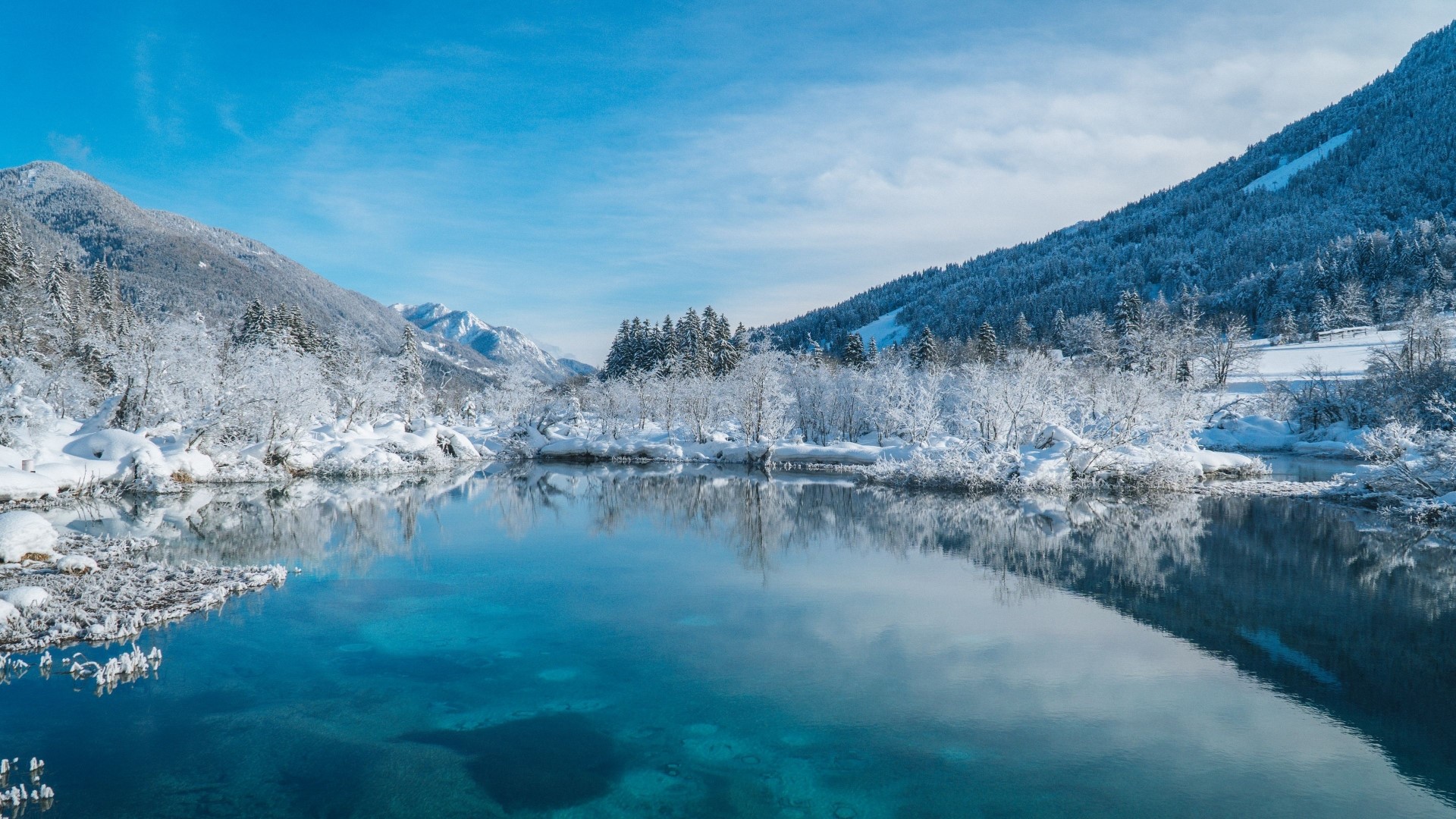 Snowy mountains and trees reflected in a clear blue lake HD Wallpaper