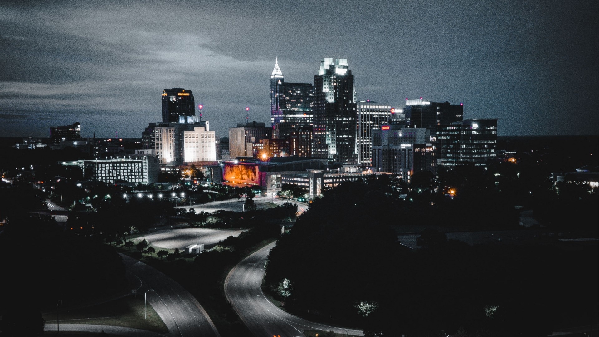 Night city skyline with illuminated buildings and roads HD Wallpaper