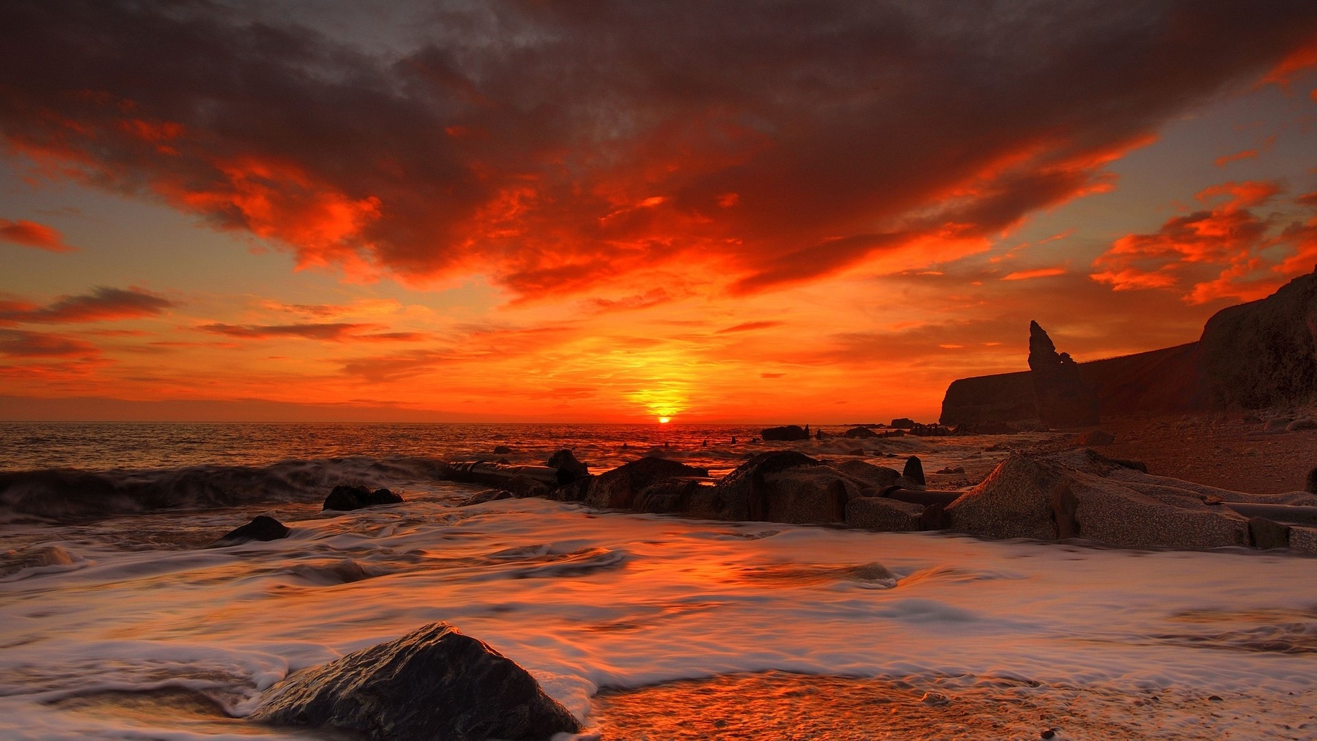 Sunset over the ocean with rocky shore HD Wallpaper