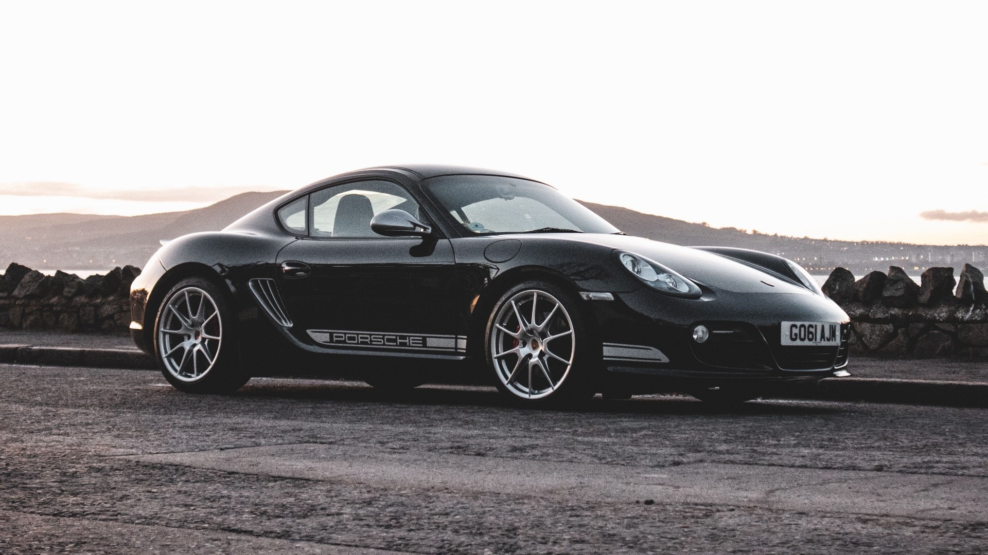 Black Porsche Cayman 987 R parked by a stone wall HD Wallpaper