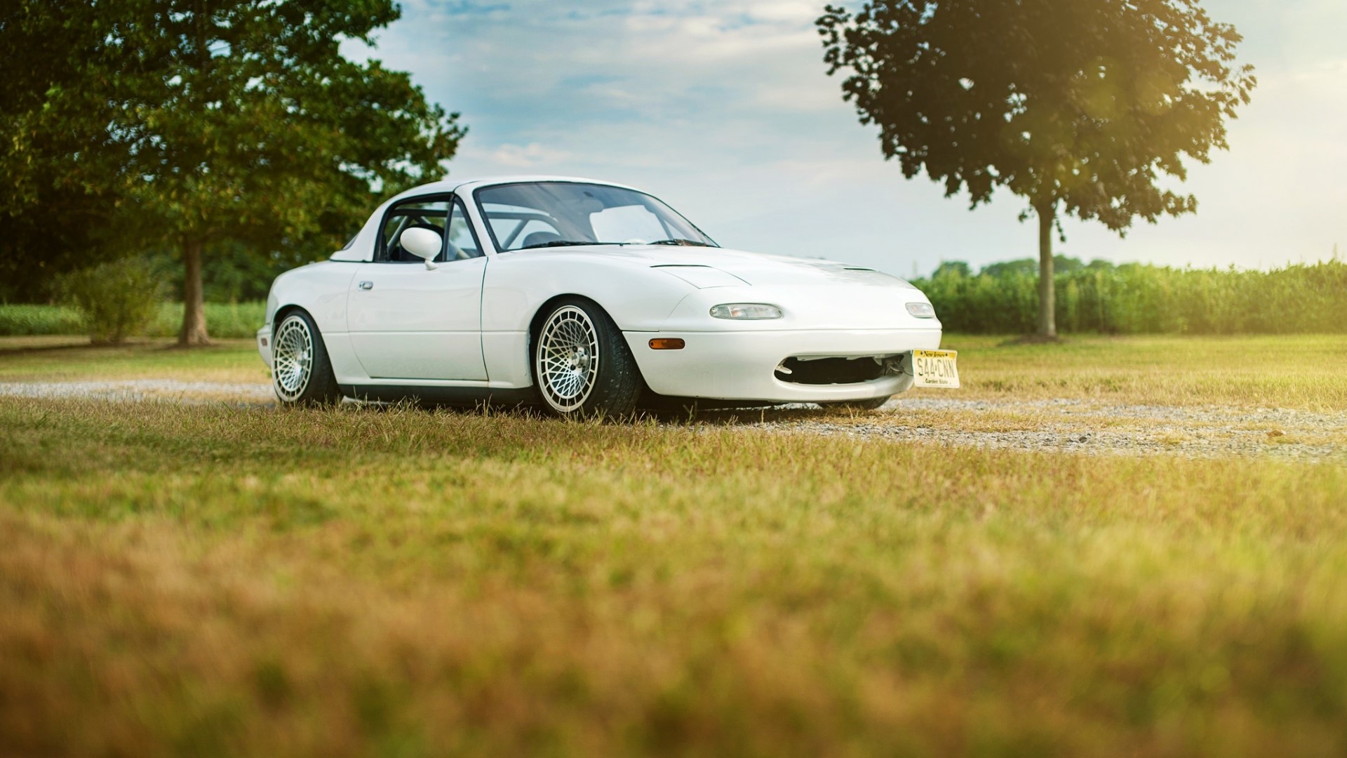White Mazda Miata parked on gravel road HD Wallpaper
