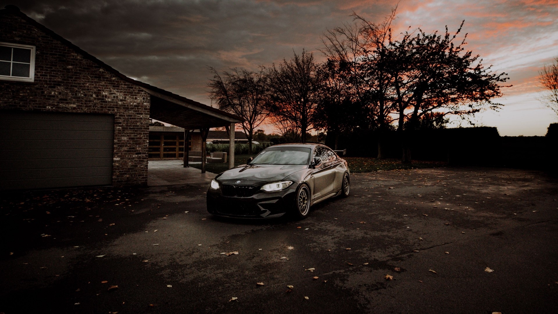 BMW M2 parked near a brick house at sunset HD Wallpaper