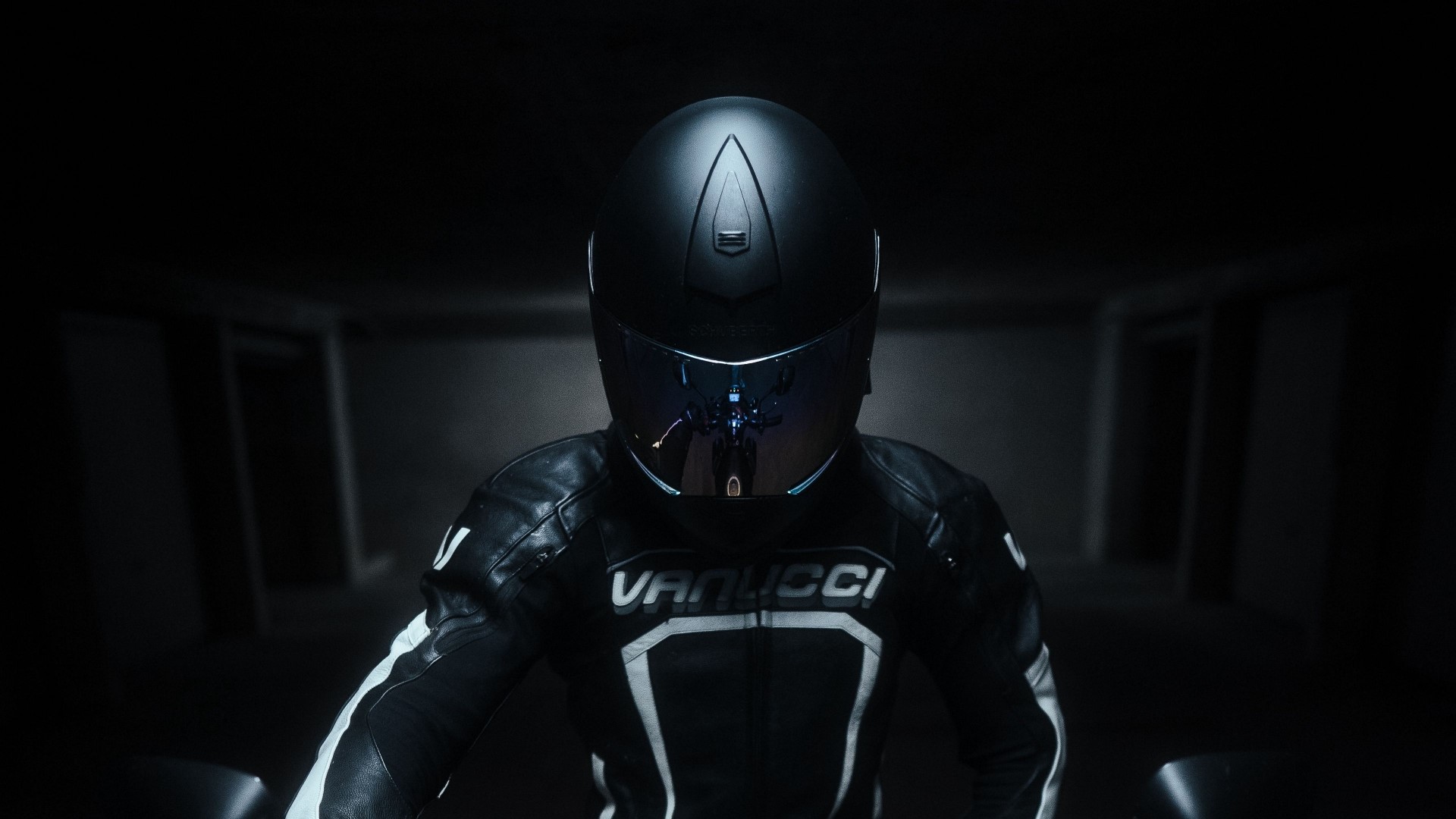 Motorcyclist wearing a black Vanucci racing suit and helmet HD Wallpaper